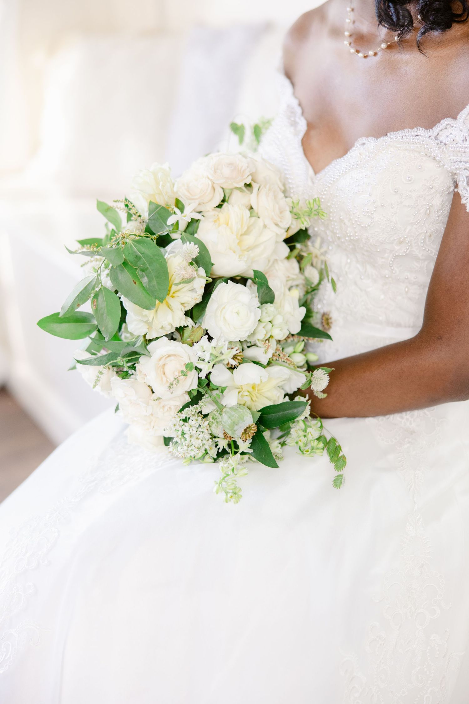 Elegant white and green bridal bouquet featuring hydrangeas and delicate foliage against a light background.
