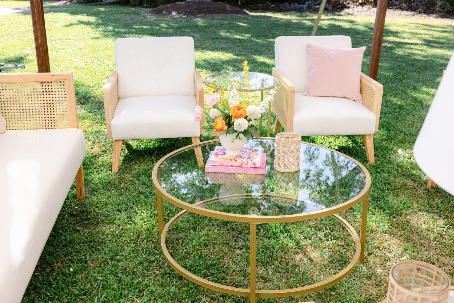Wedding lounge setup featuring white and pink furniture with gold accents in a garden setting.