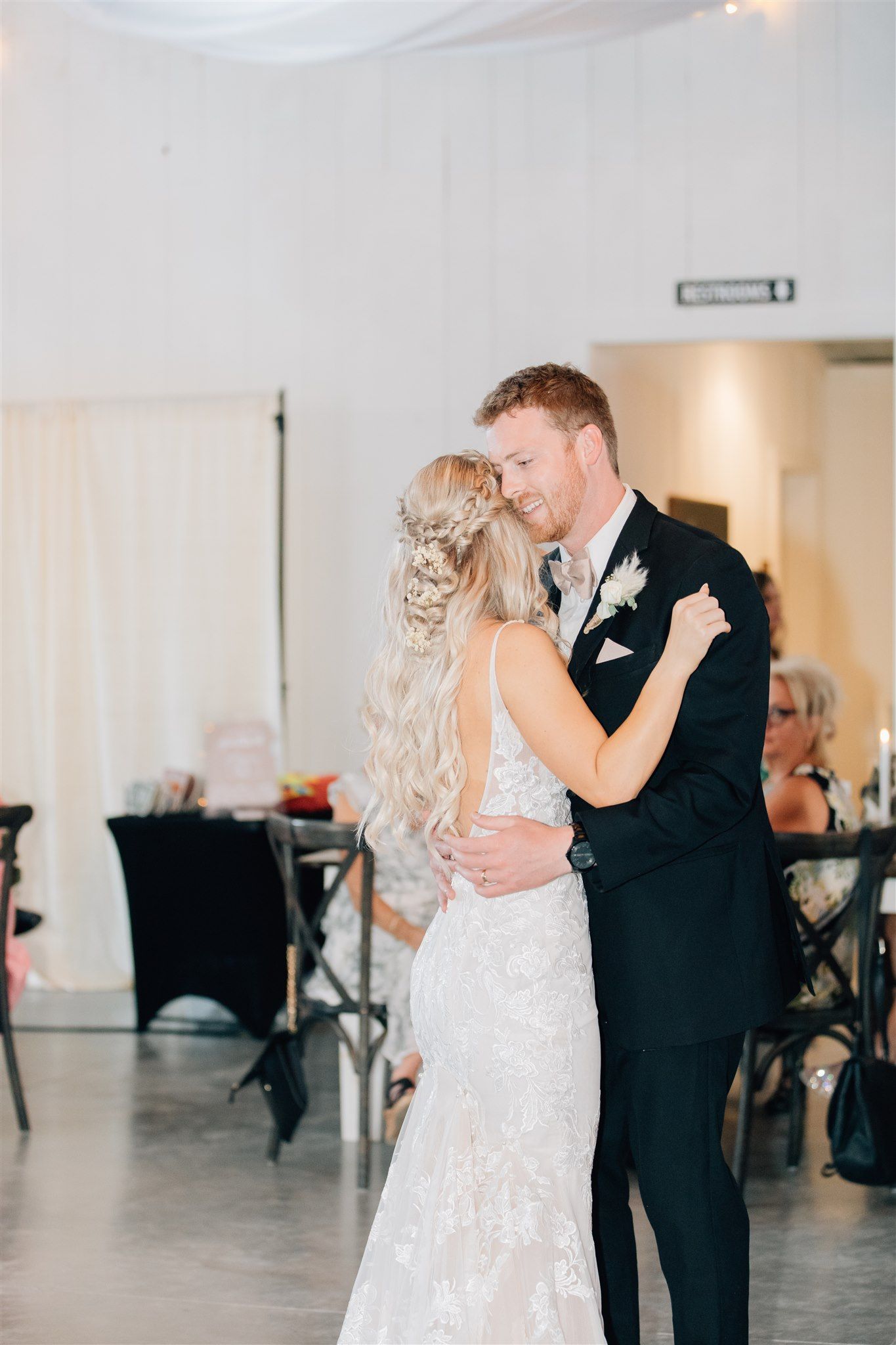 Newlyweds share their first dance in elegant white-draped reception venue.