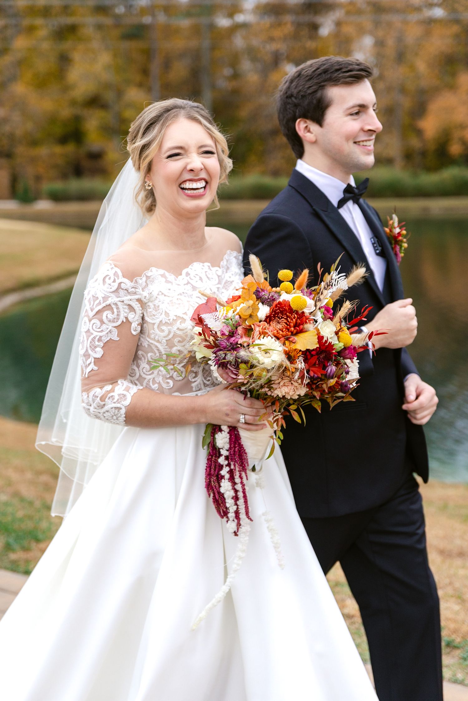 Autumn wedding photoshoot with fall-colored bouquet by a lakeside.