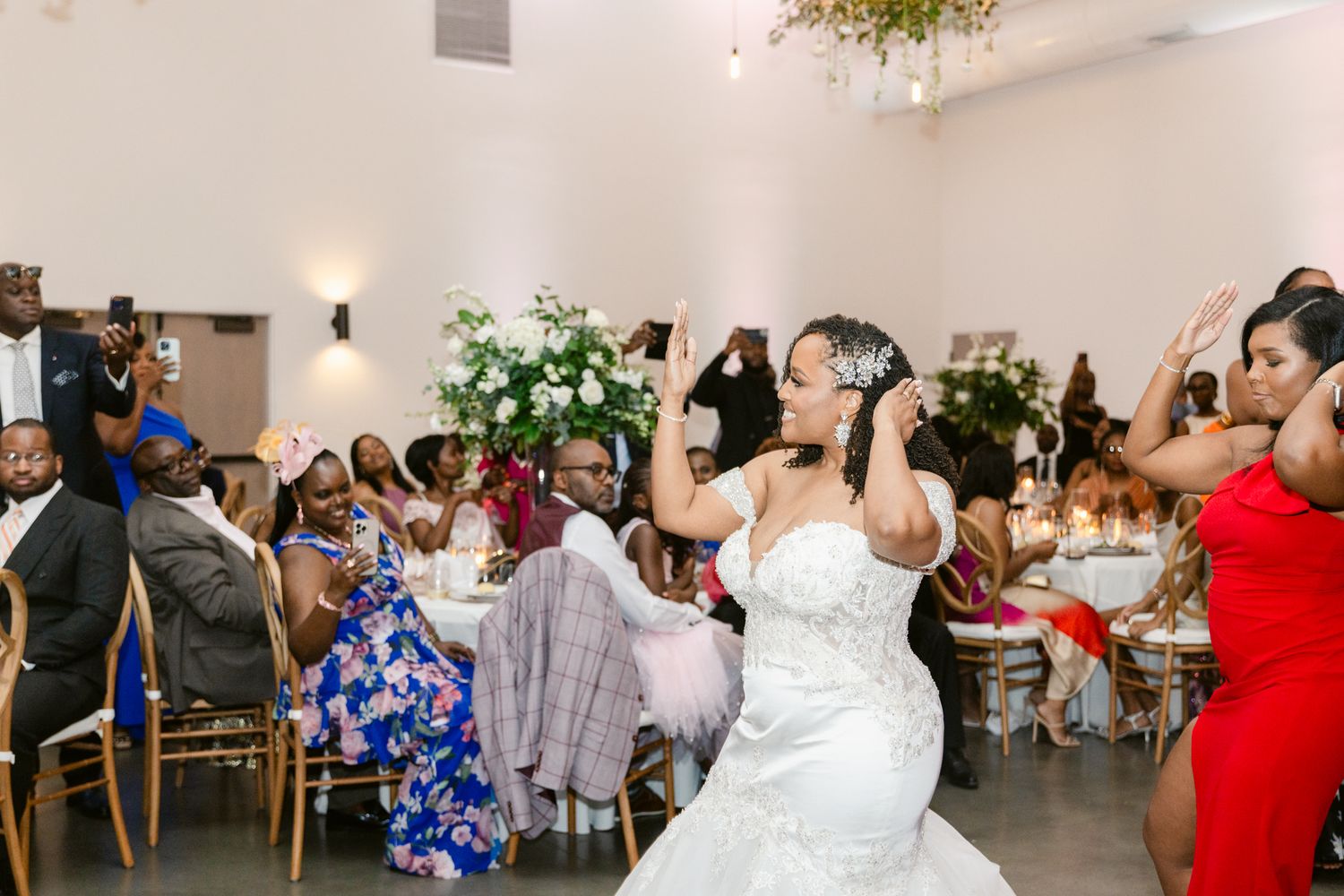 Wedding celebration showing guests dancing and mingling in a bright white reception space.