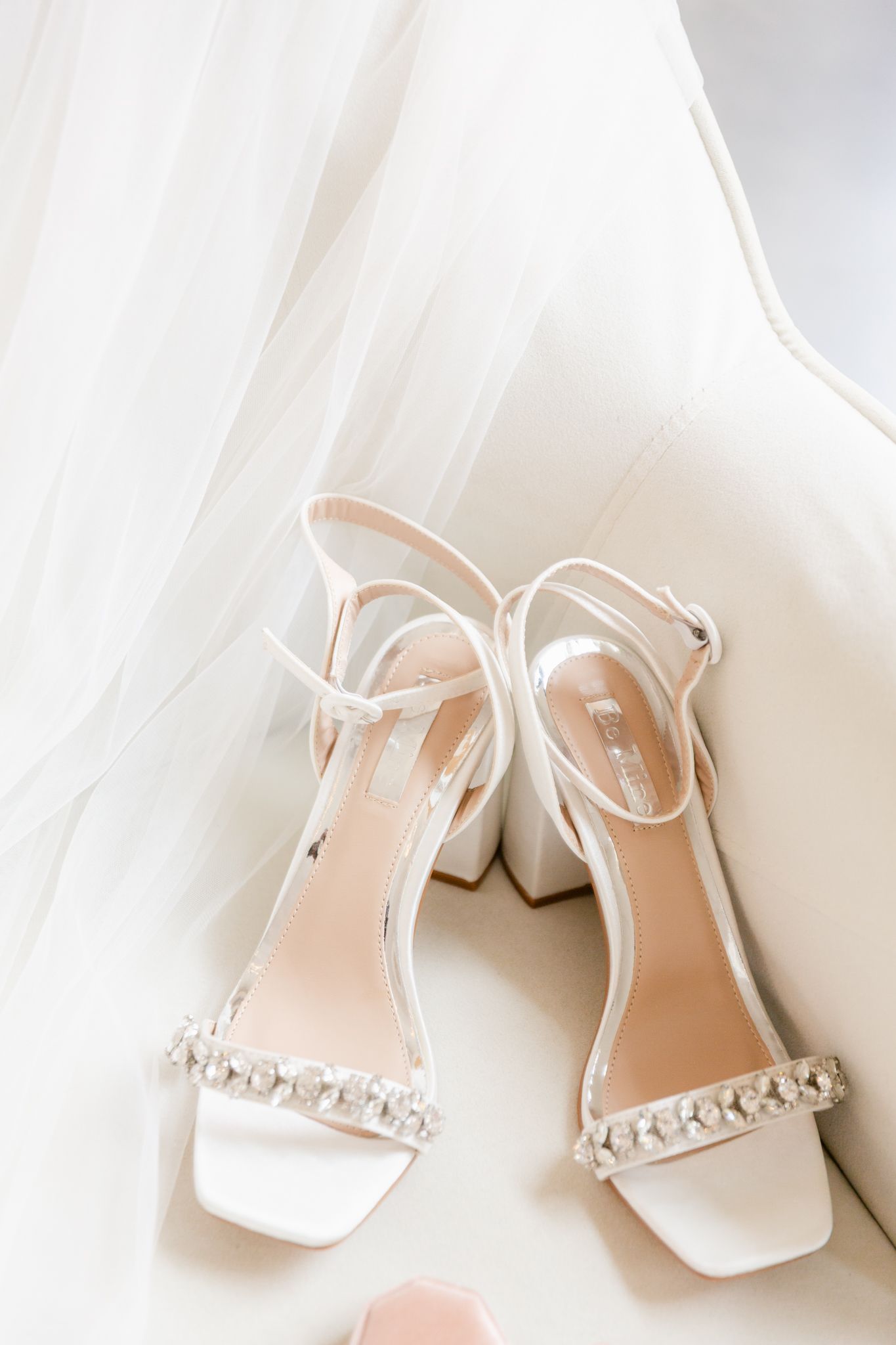 Elegant white bridal sandals with crystal embellishments and block heels displayed against a light background.