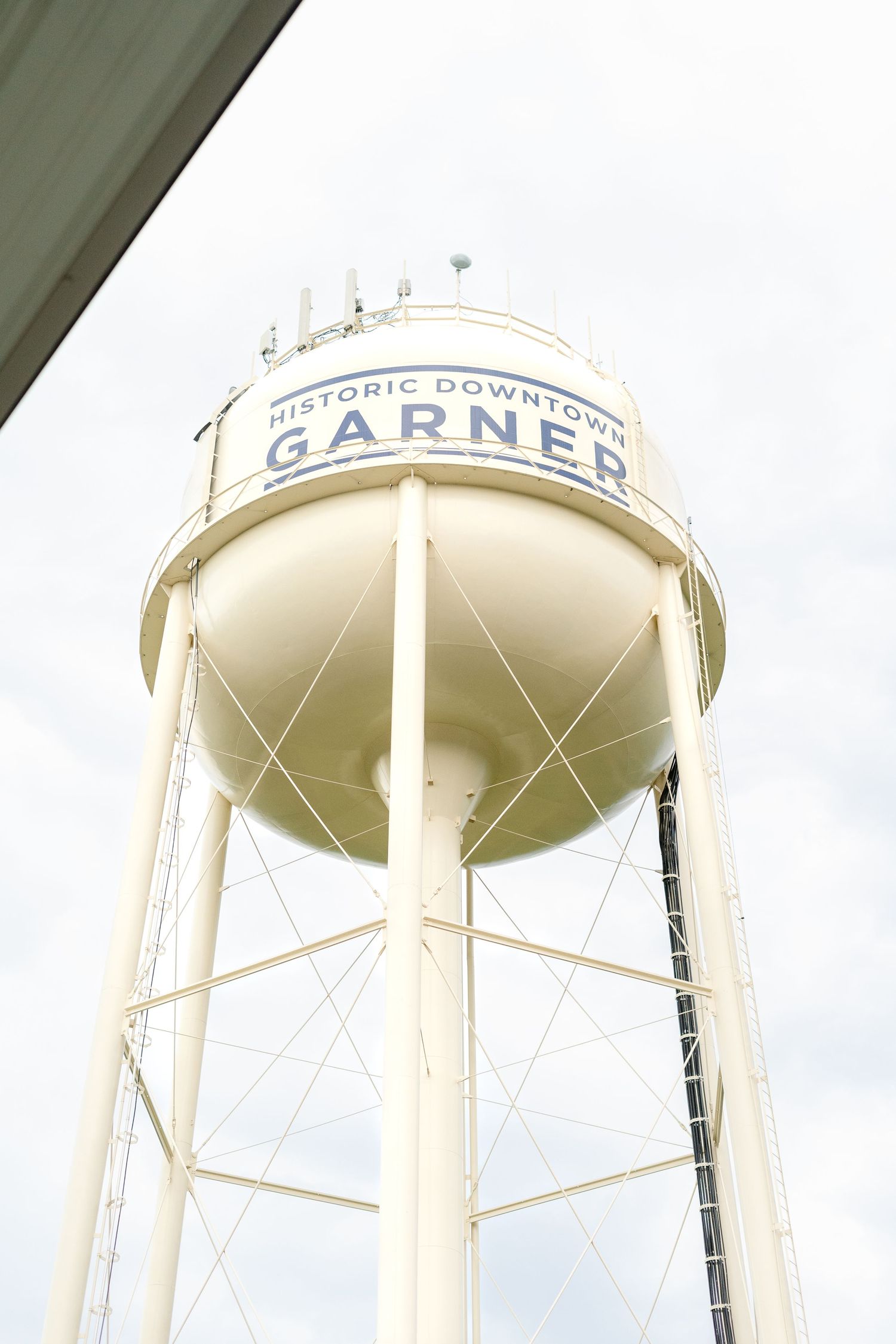 Three tall white water towers stand against a cloudy sky, with Garner text visible on one tower.