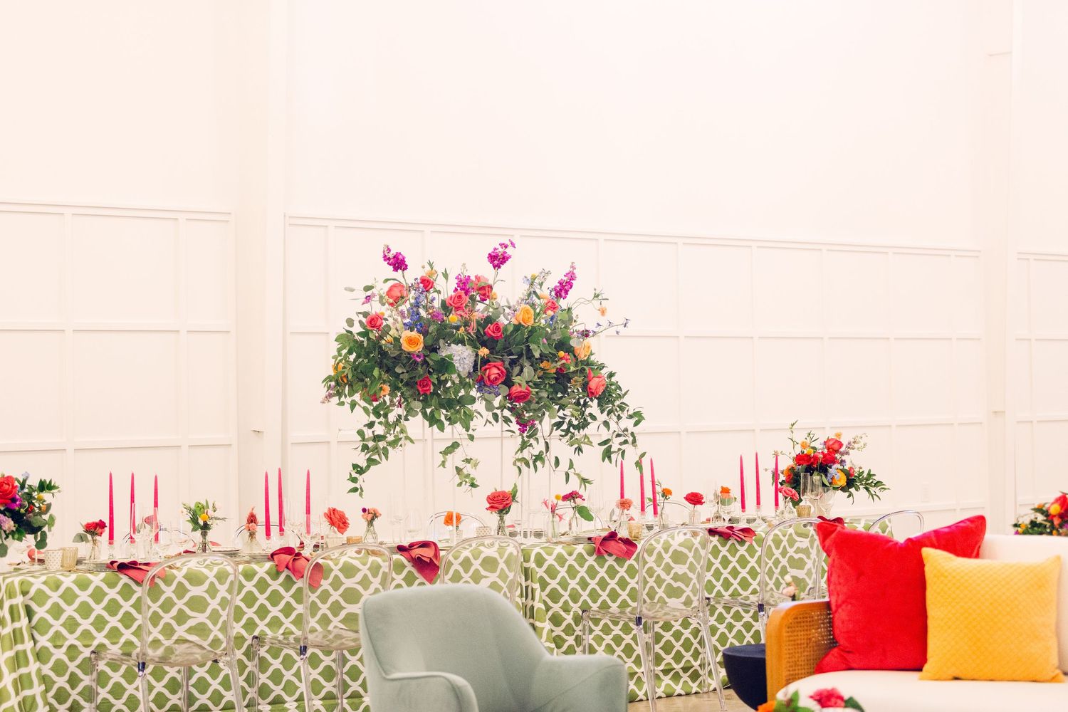 Bright floral arrangements and colorful throw pillows decorate a white lattice backdrop.