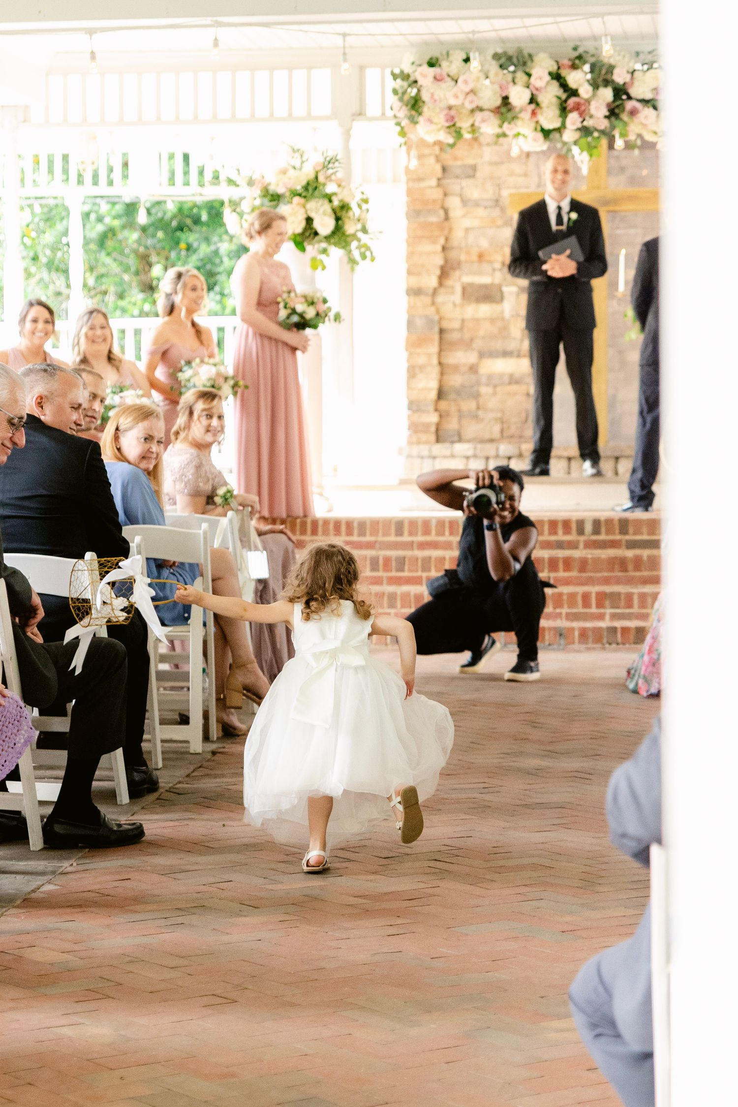 A series of wedding party members running across a brick patio during a fun wedding photo session.