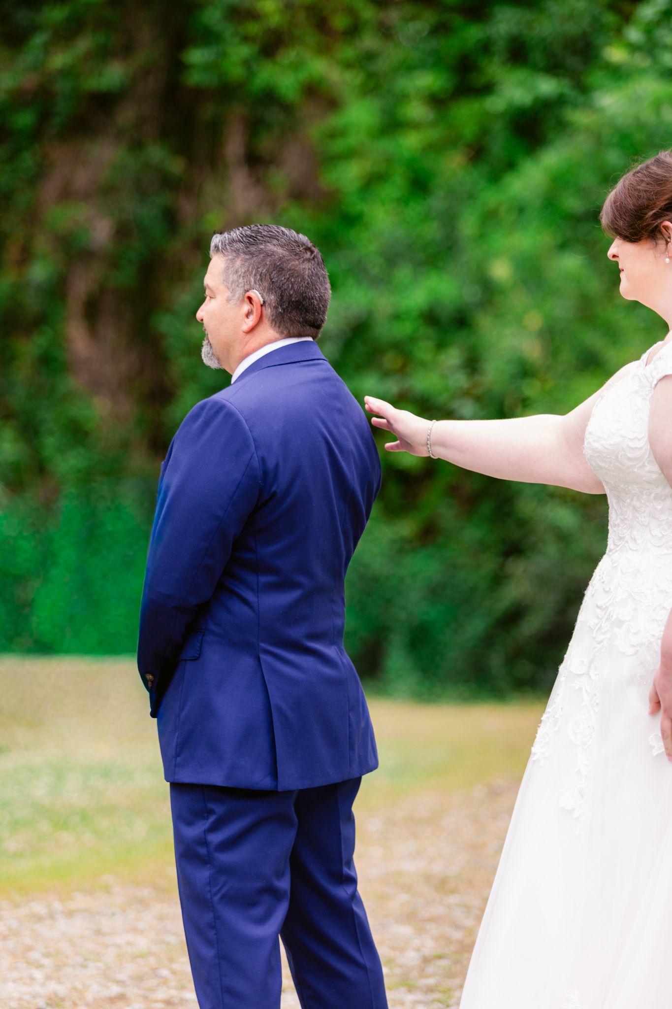 A playful wedding moment captured outdoors with a bride in white dress and groom in navy suit.