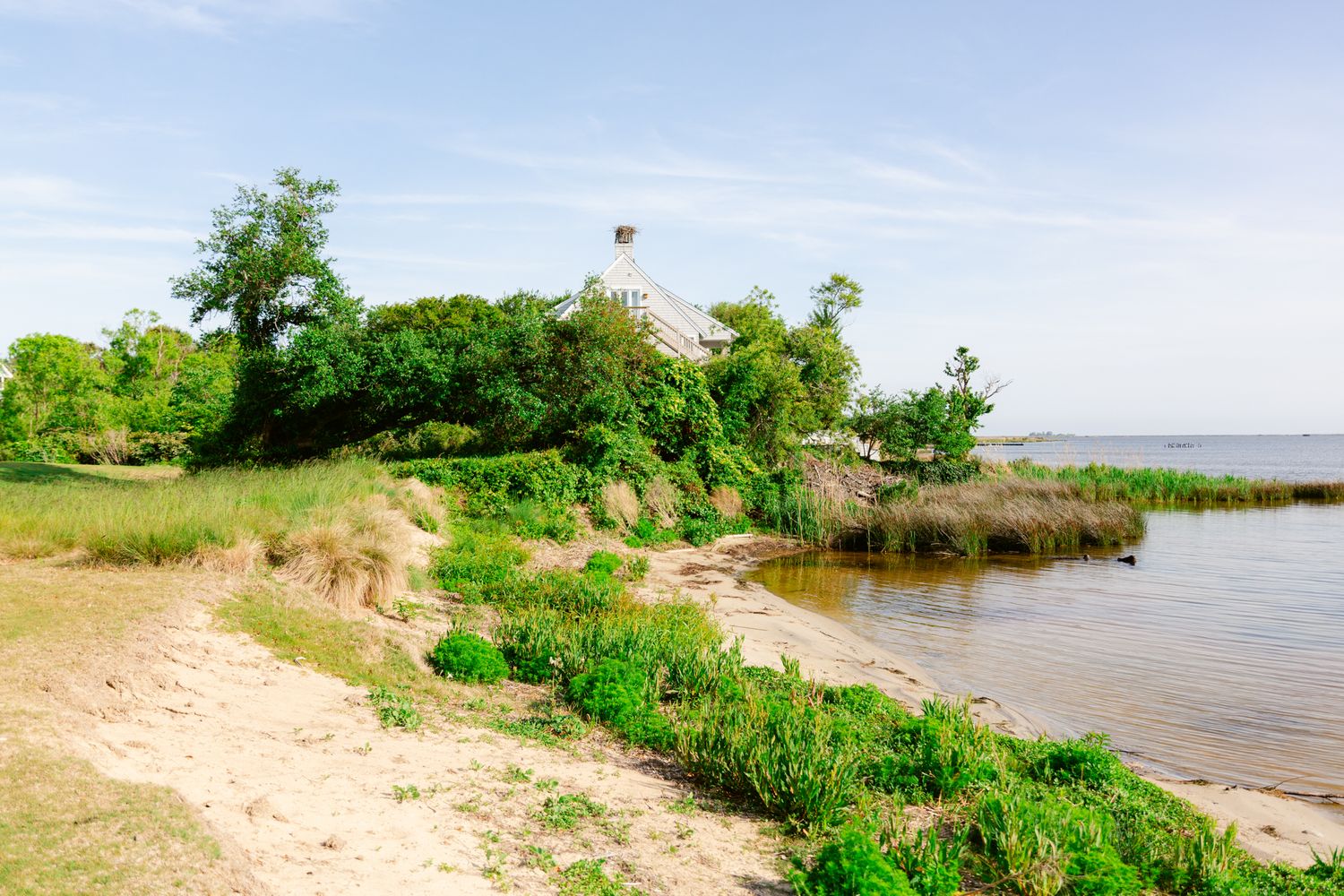 A scenic coastal landscape with sandy beaches, lush green vegetation, and calm waters stretches along the shoreline.
