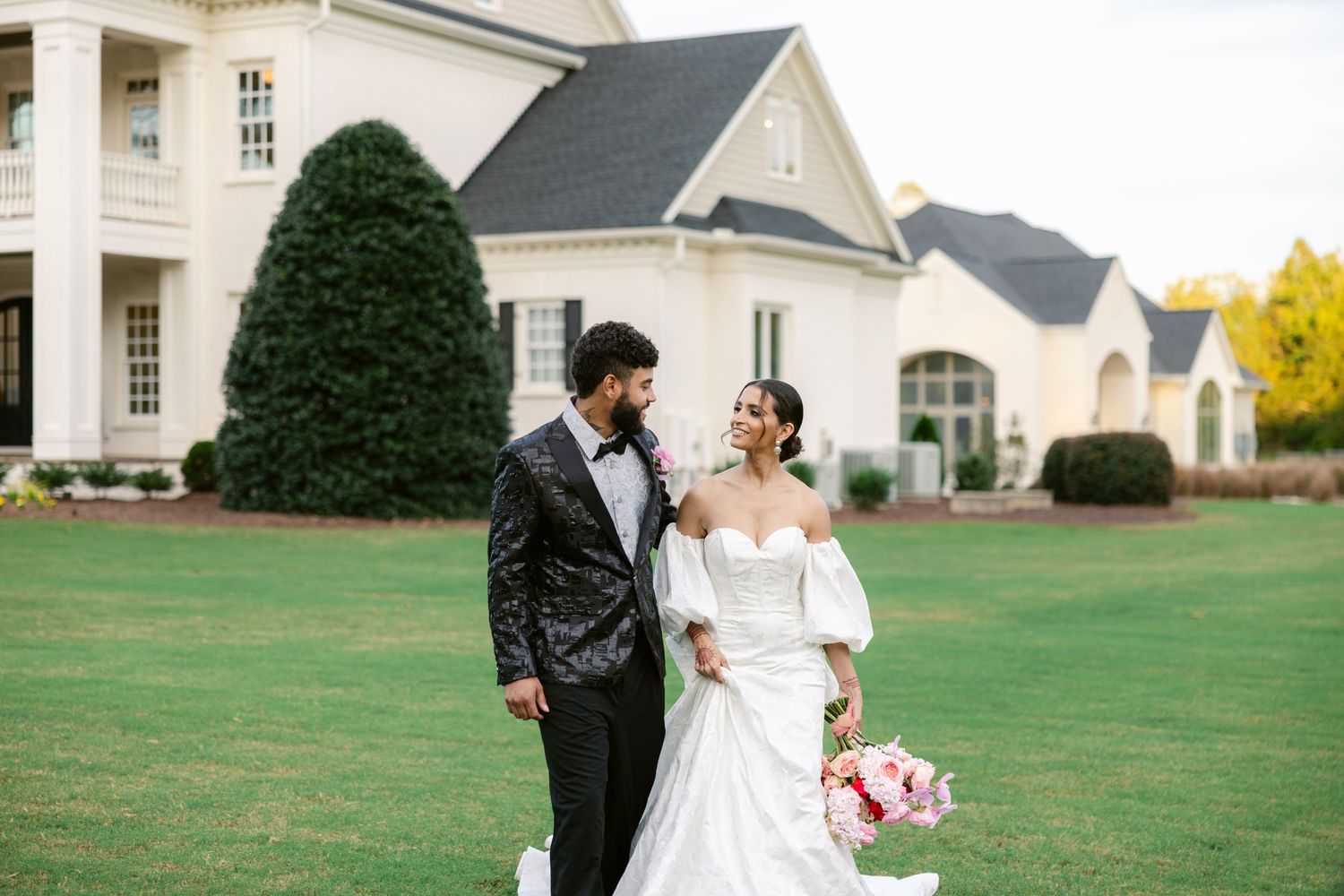 Wedding venue exterior featuring a classic white mansion with manicured lawns and gardens.