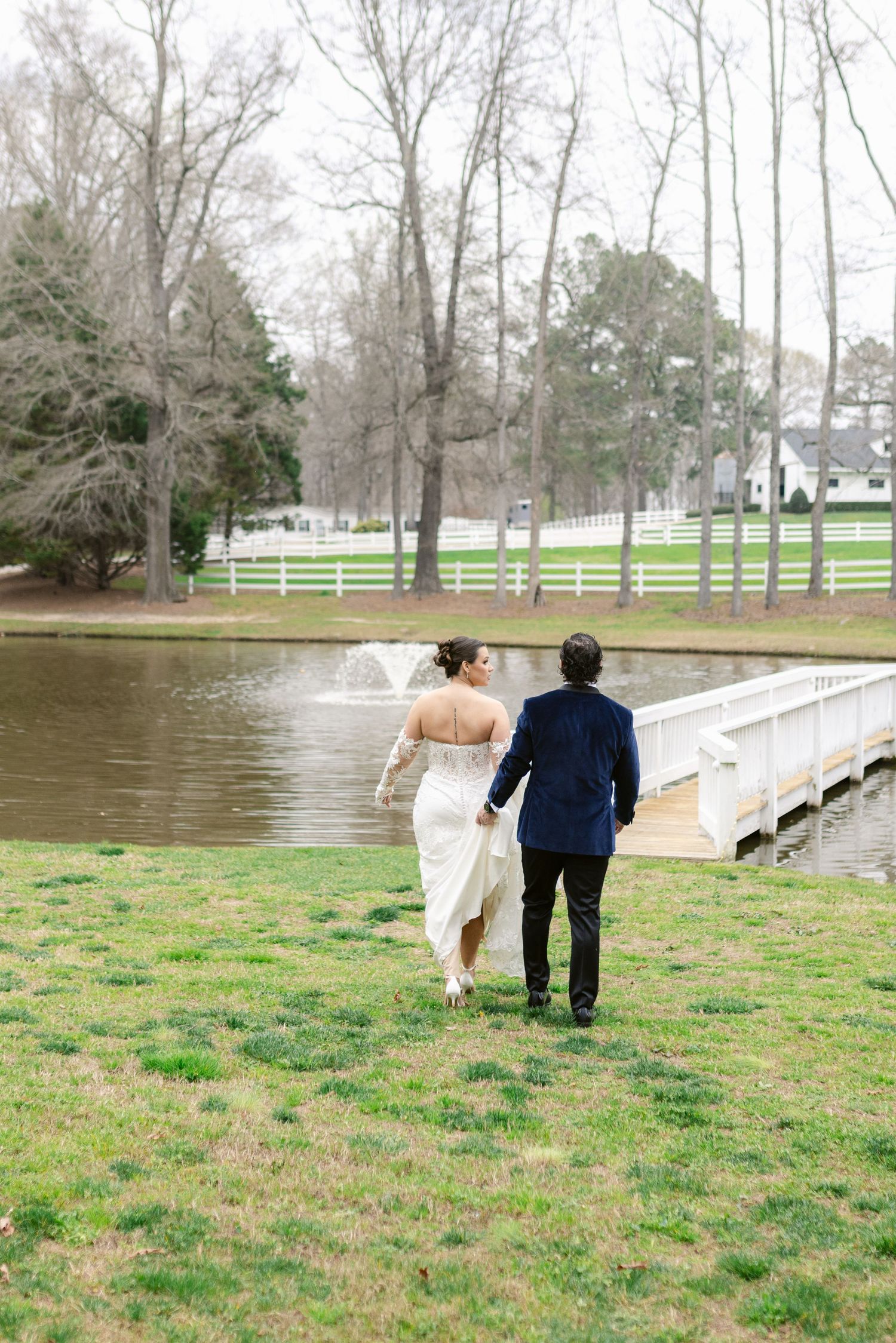 A couple walks along a wooden dock beside a flooded grassy field on an overcast winter day.
