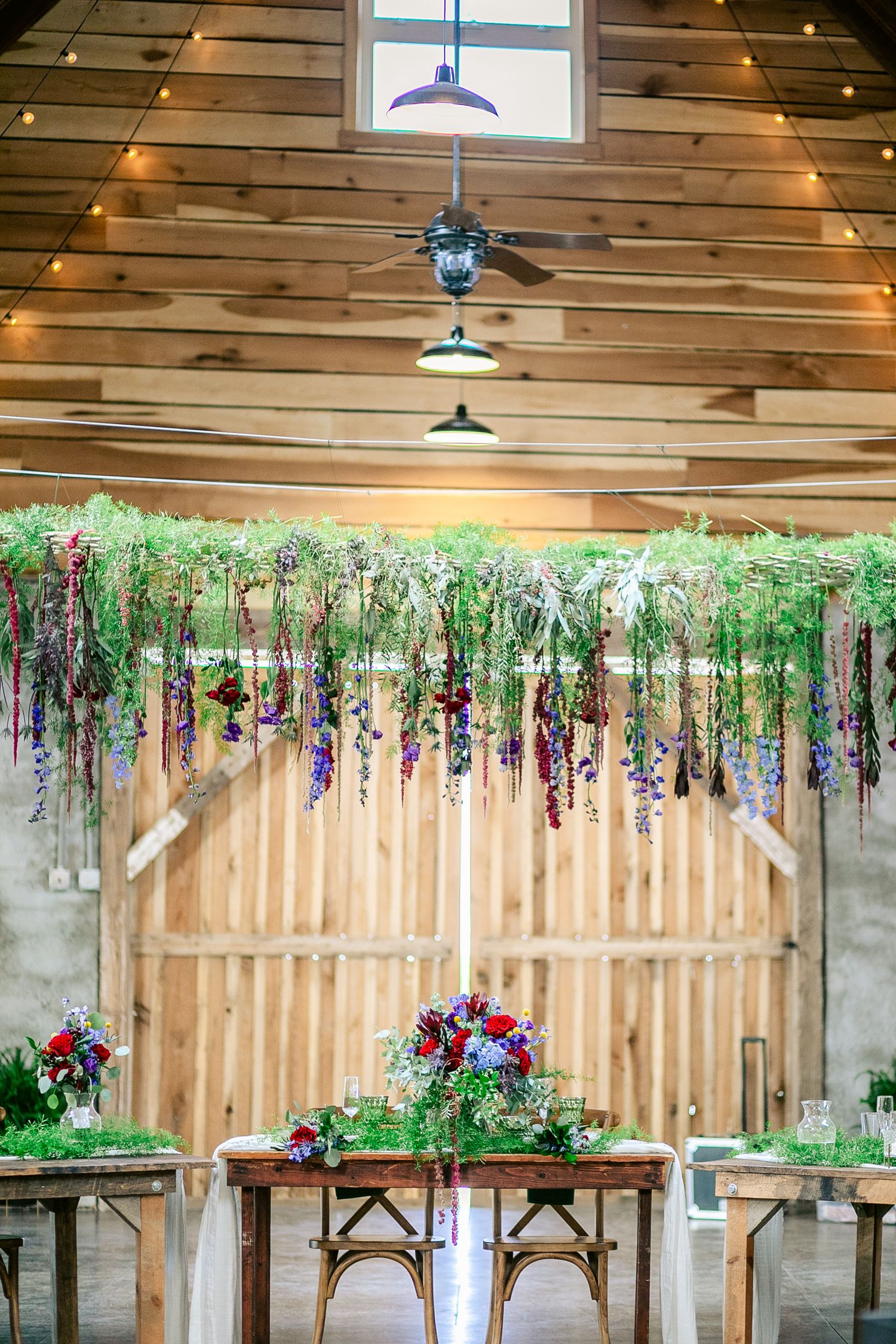 Rustic barn wedding venue with hanging floral decor and wooden chairs set for a romantic ceremony.