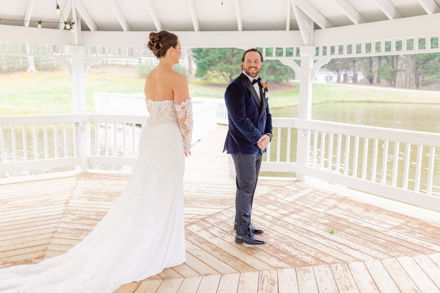 A couple share their first look moment under a white gazebo during their wedding day.