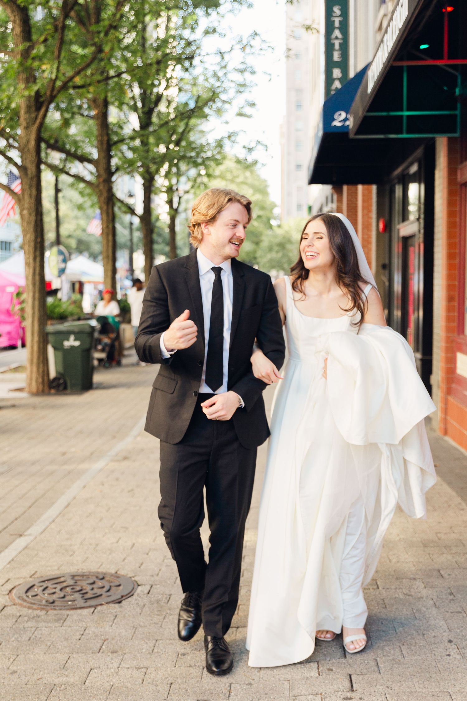 A joyful couple walking down a city street after their wedding ceremony.