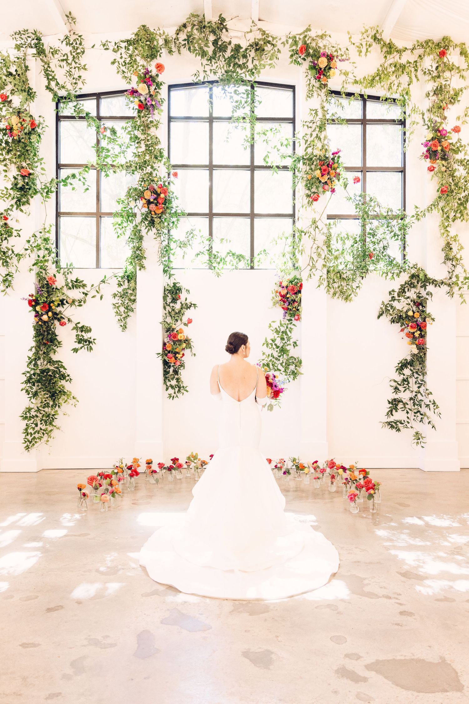 Bright wedding venue with sunlit windows adorned with trailing floral arrangements and greenery.