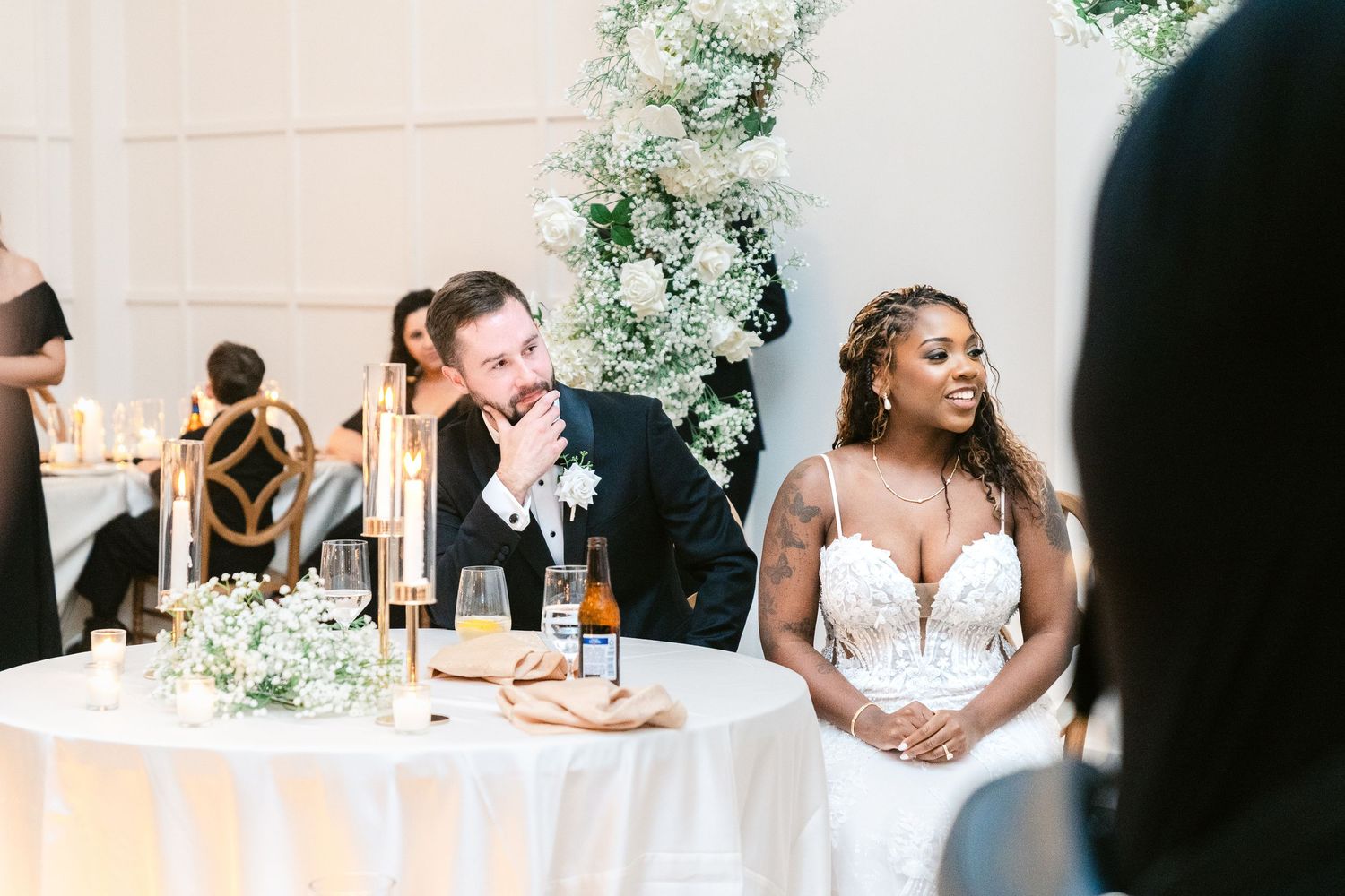 Elegant wedding reception setup with white floral arrangements and soft lighting.