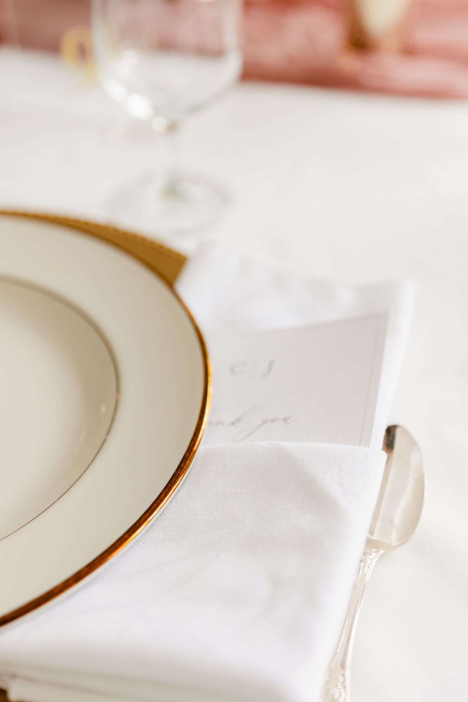 White linen napkins with gold-rimmed plates set elegantly in a row at a formal dining table.