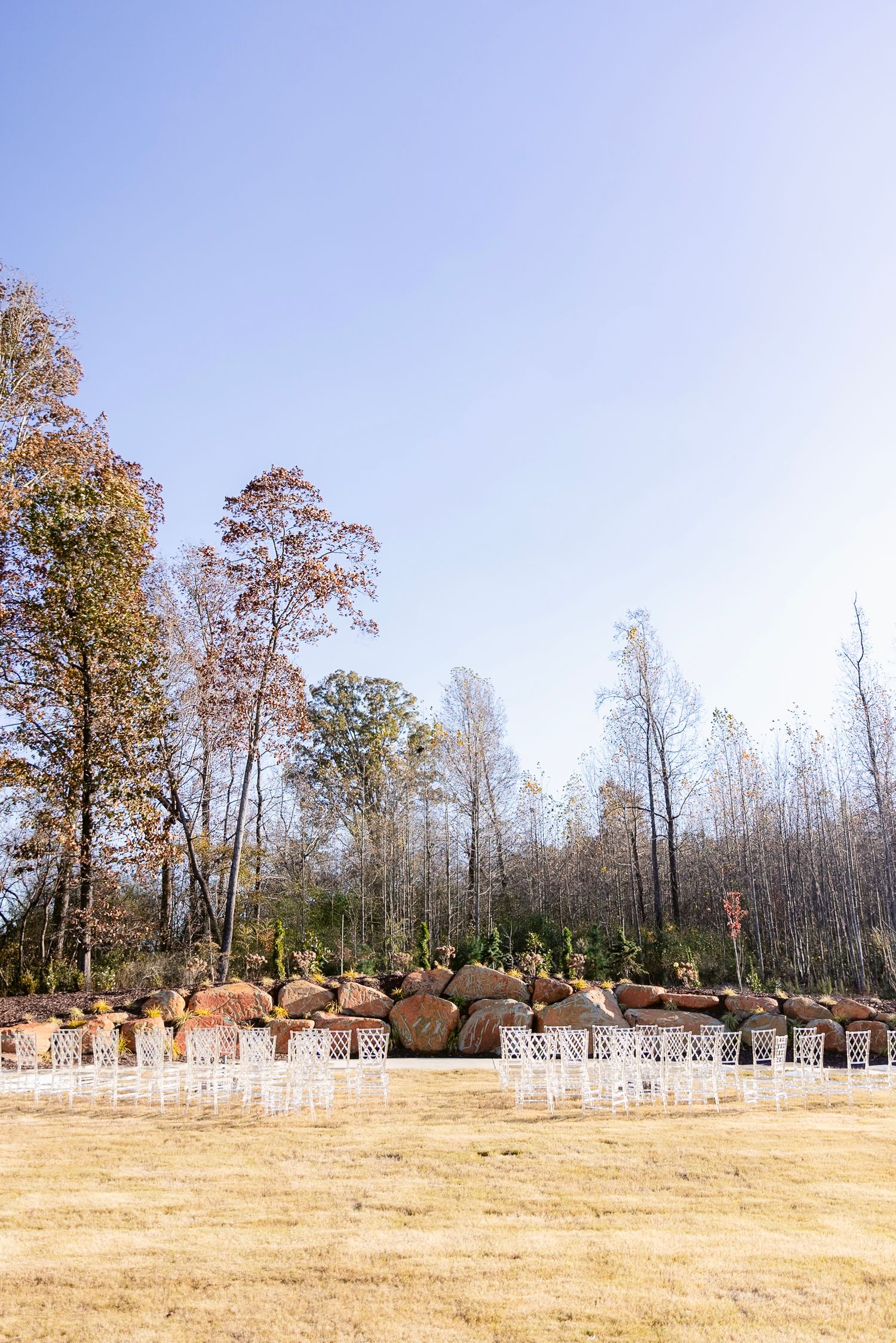 A panoramic view of a brown grassy field with bare trees and wooden fences stretching across the horizon.