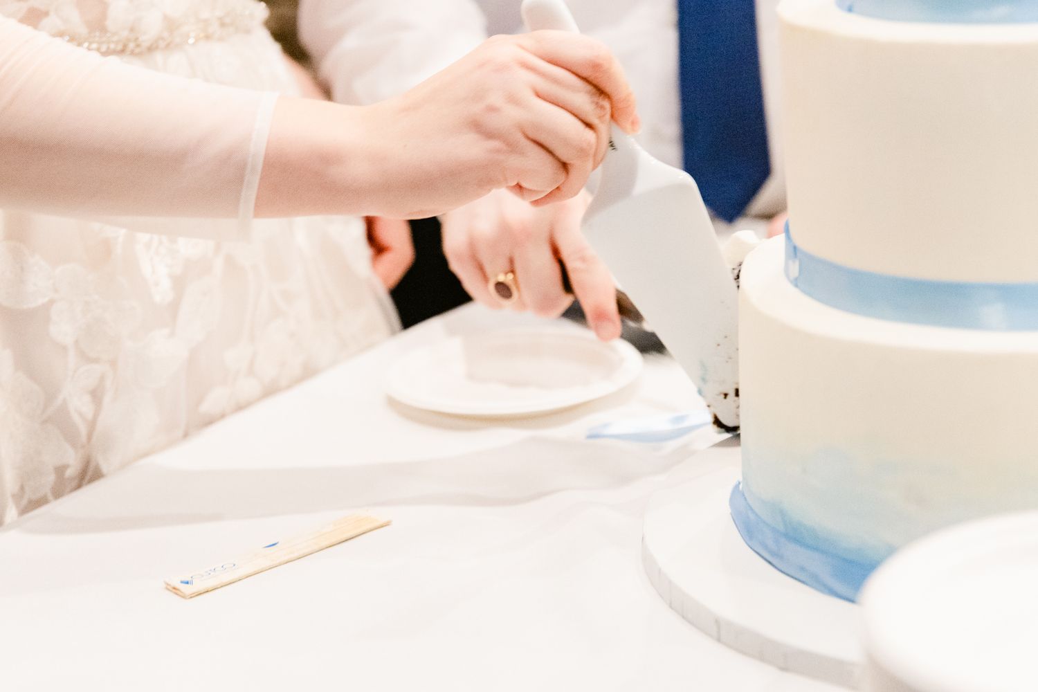 A close-up view of hands mixing ingredients in a white bowl using a wooden spoon.