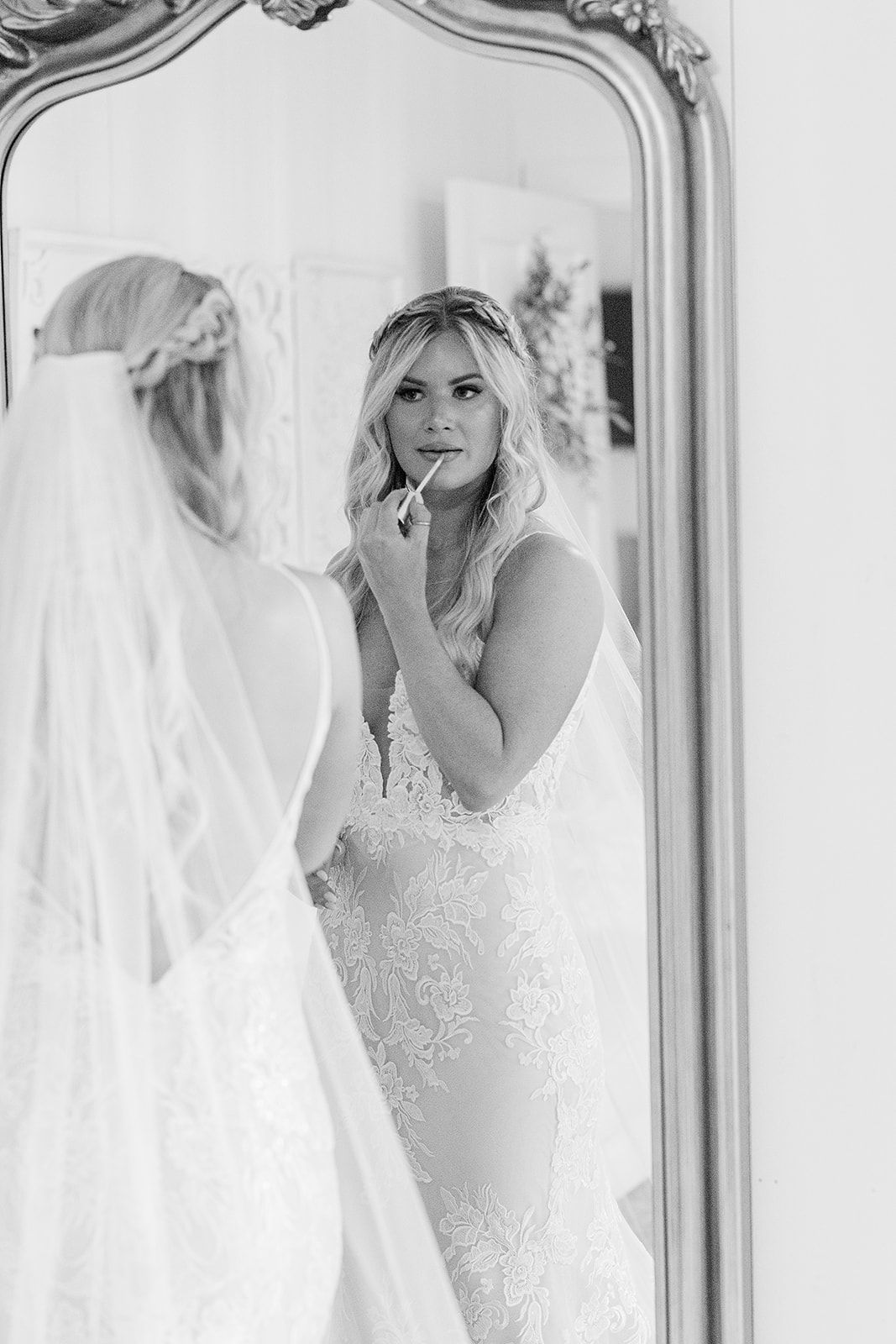 Classic black and white bridal portrait reflected in ornate vintage mirror.