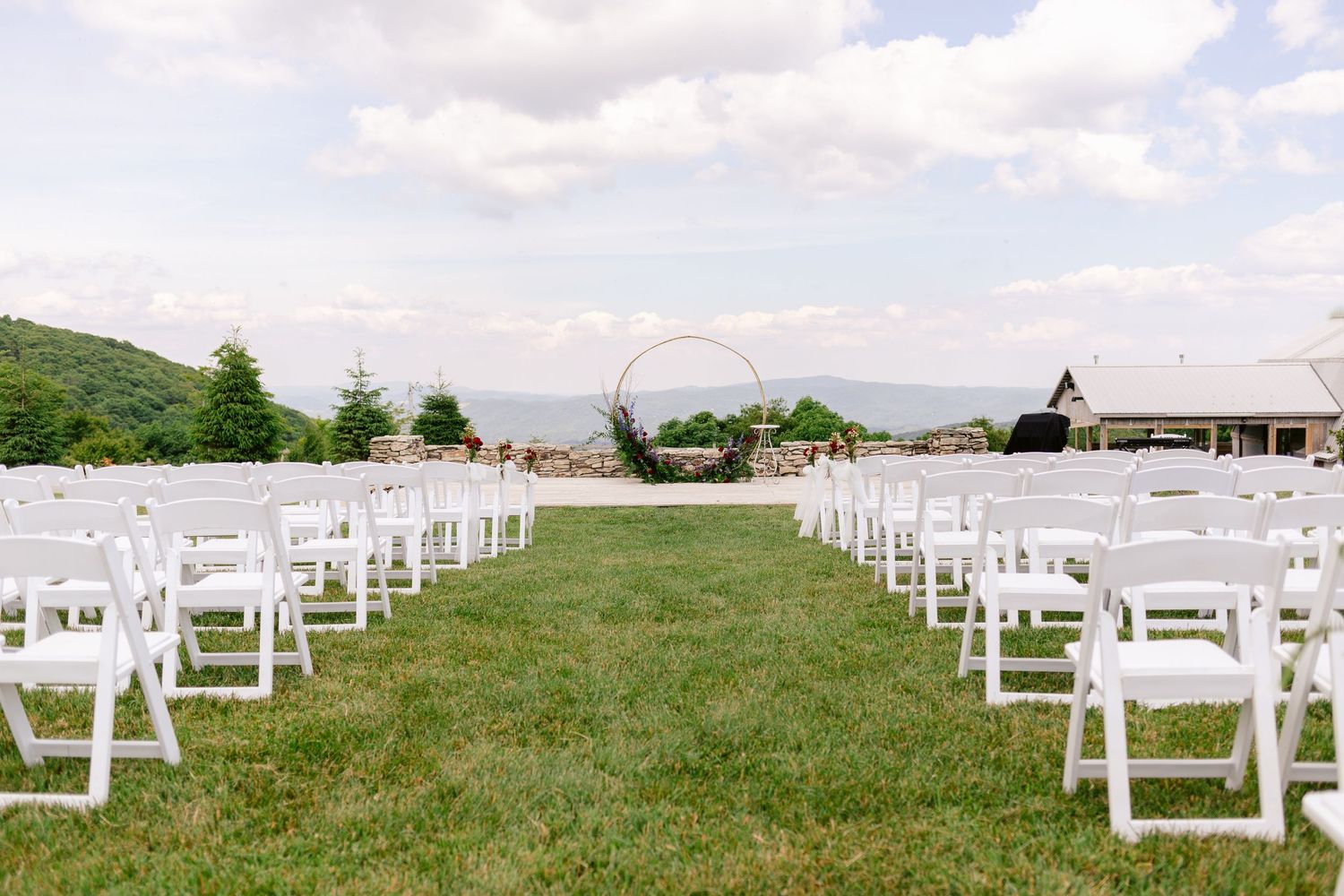 Rows of white chairs set up for an outdoor wedding ceremony with mountain views.