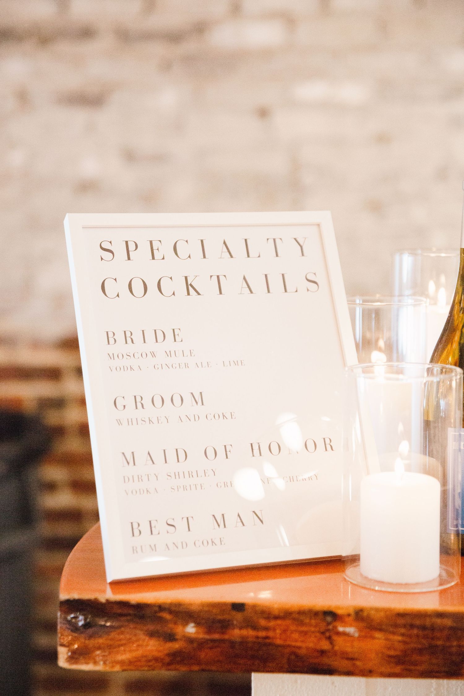 Specialty cocktails menu sign for wedding party displayed on wooden surface.