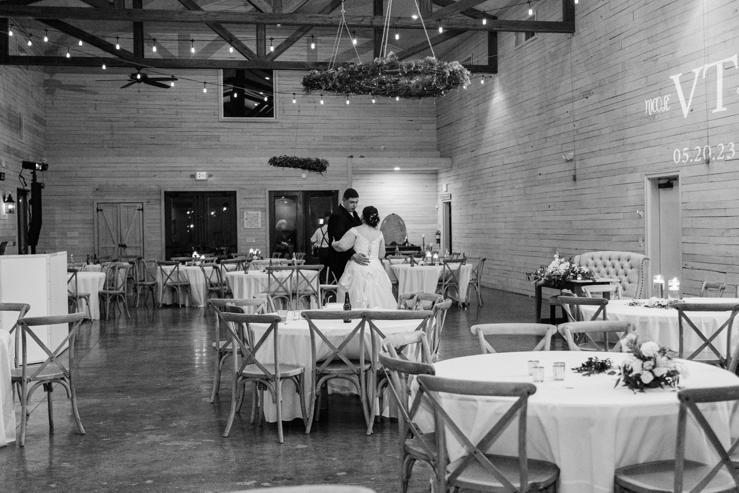 An elegant reception hall with round tables and white linens set up for a wedding celebration.