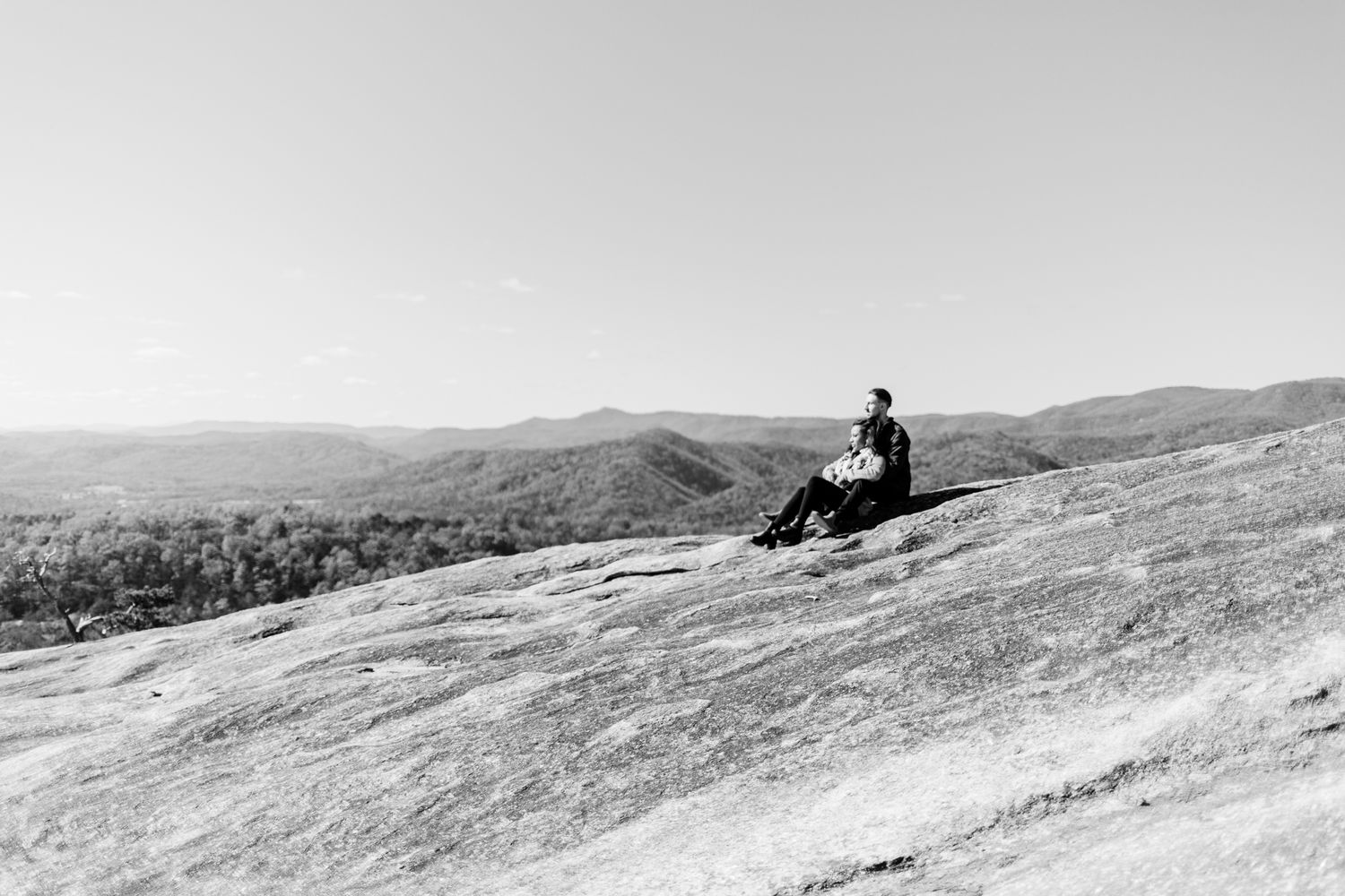 Black and white landscape photo of people enjoying a scenic mountain vista on a clear day.