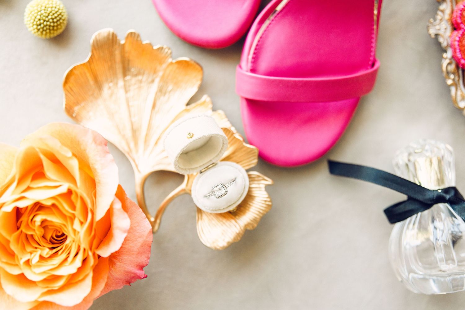 Pink sandals displayed with peach roses and perfume bottle on light background.