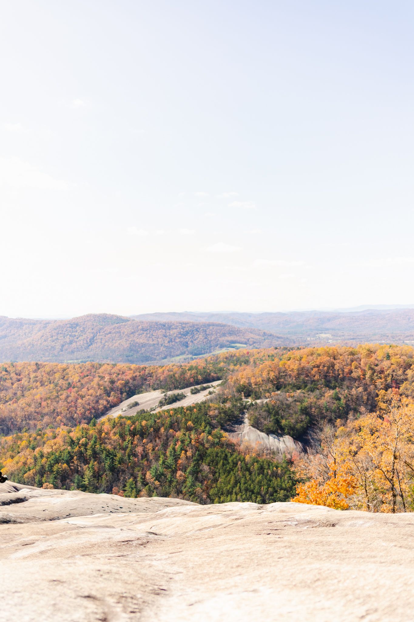 Panoramic view of autumn forest with winding mountain roads and exposed granite rock formations in fall colors.