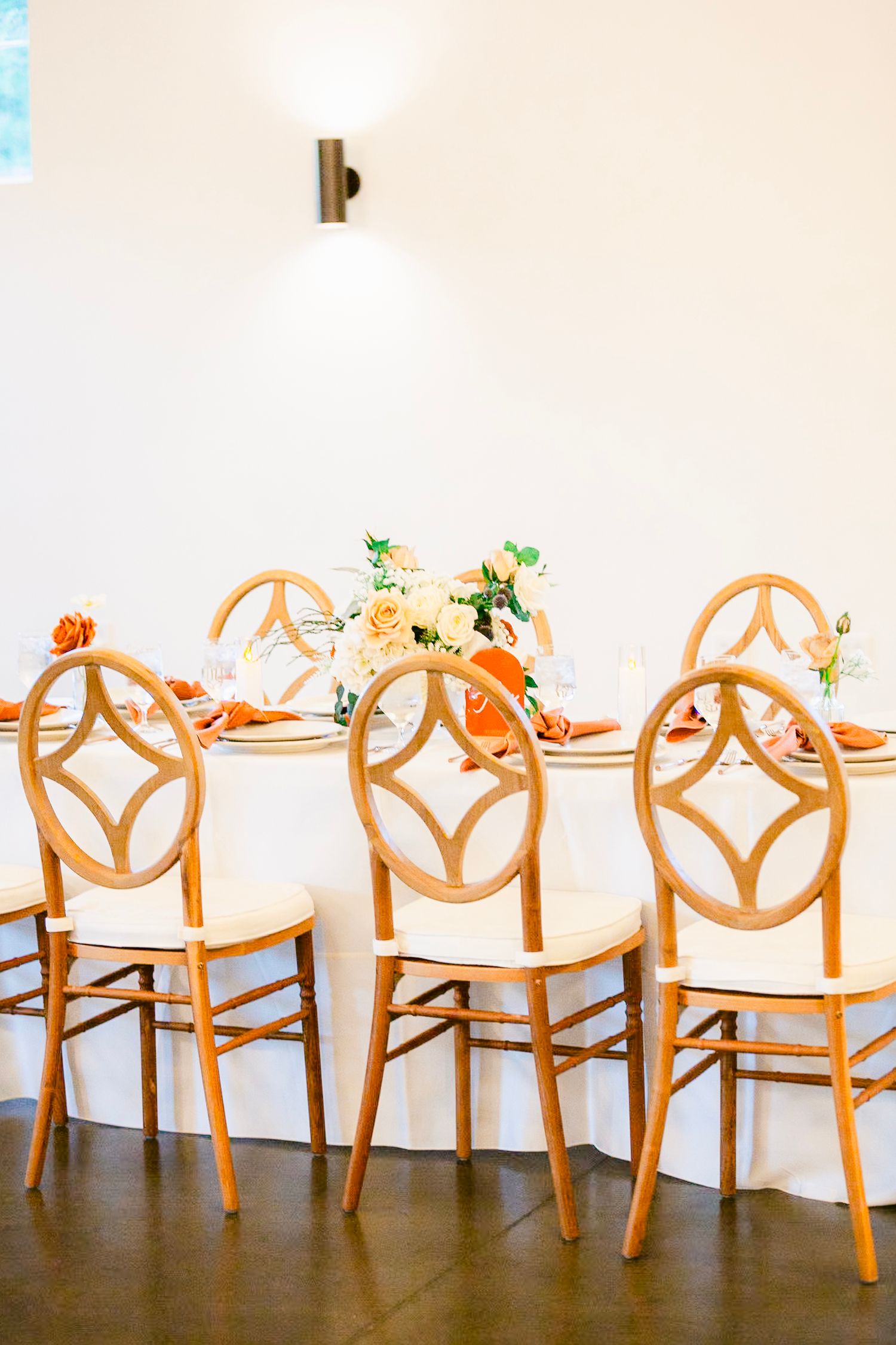 Elegant wooden chairs with geometric backs arranged at a dining table with floral centerpieces.