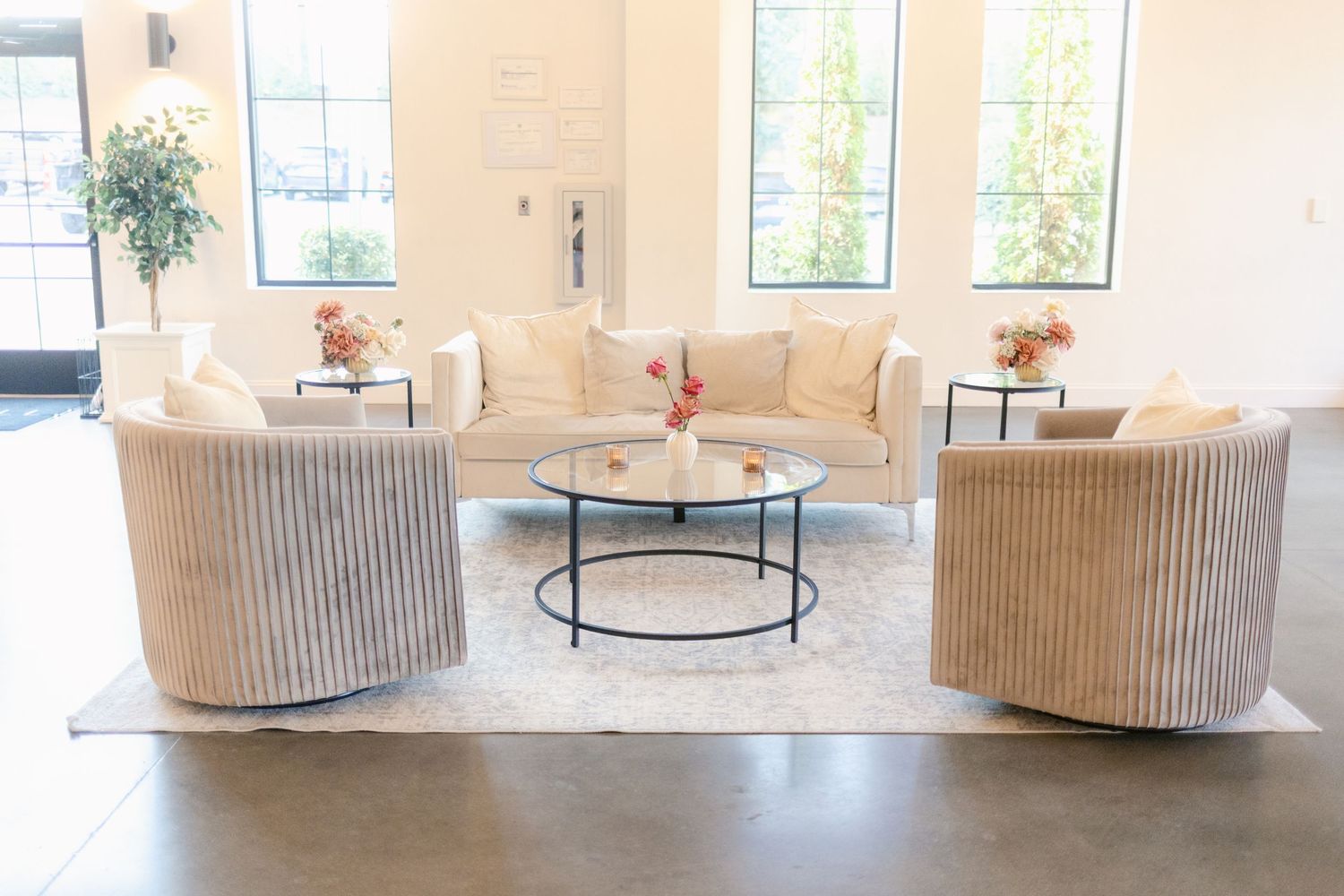 Modern hotel lobby with cream-colored armchairs, round coffee tables, and large windows letting in natural light.