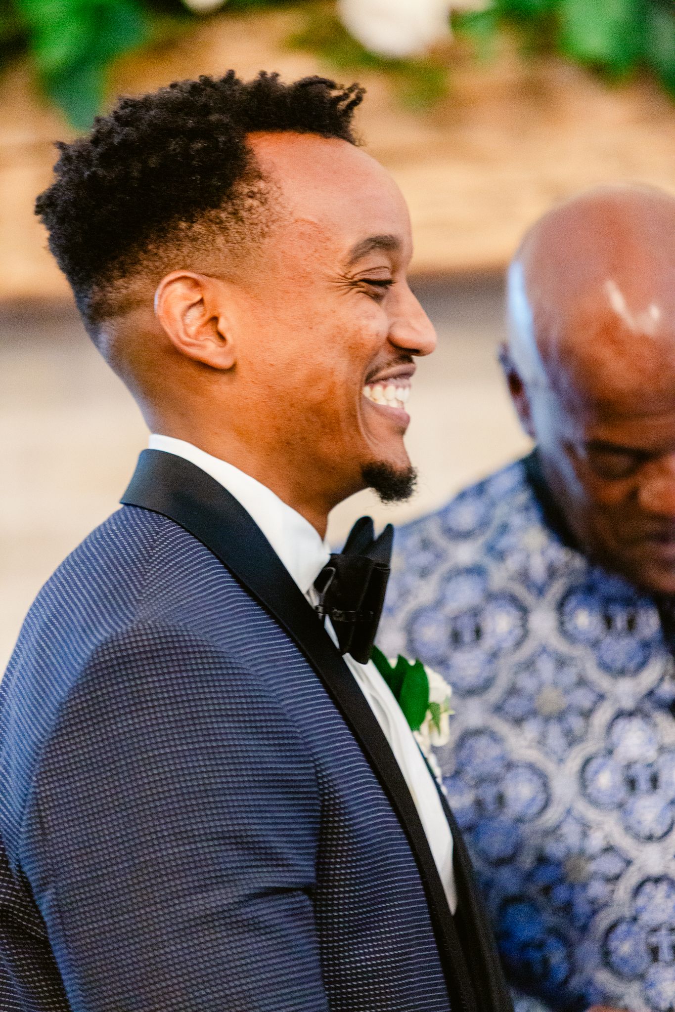 A joyful moment captured during a wedding ceremony with elegant formal attire and floral boutonniere.