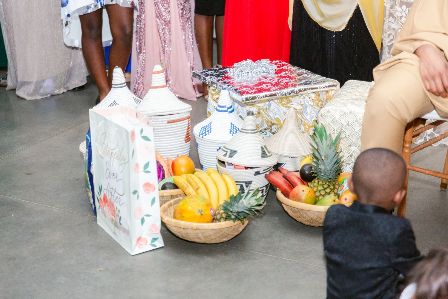 Colorful wedding gifts and fruit baskets displayed on tables at a reception.