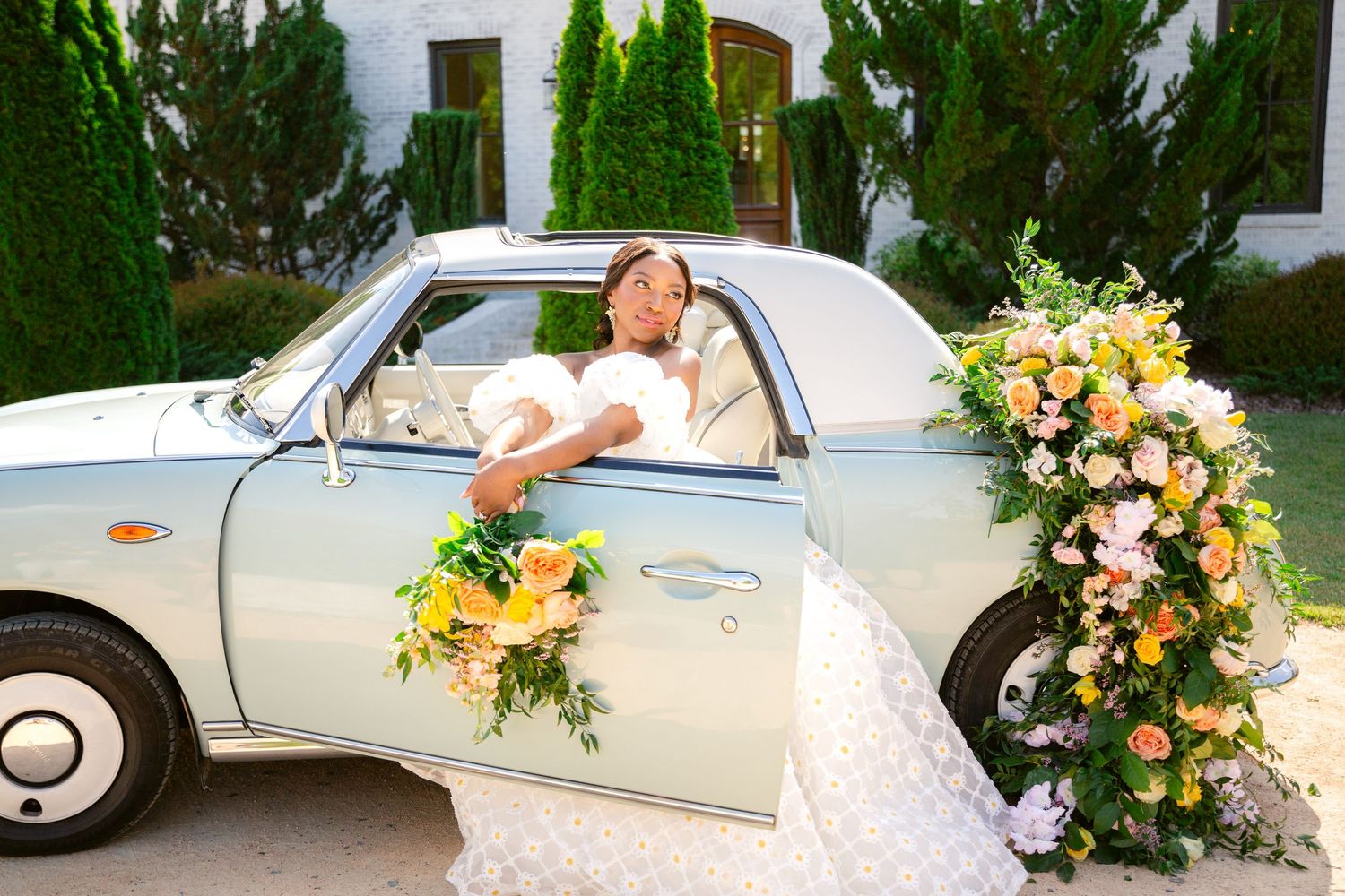 A classic white vintage car decorated with elegant floral arrangements for a wedding celebration.