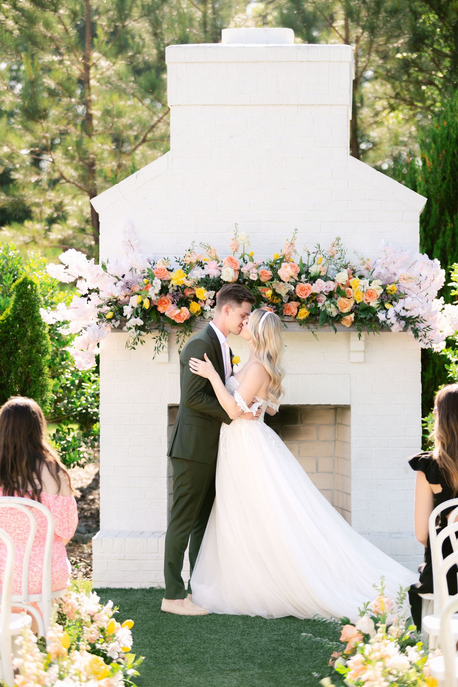 Elegant white outdoor wedding ceremony setup with floral arch and romantic decorations in a garden setting.
