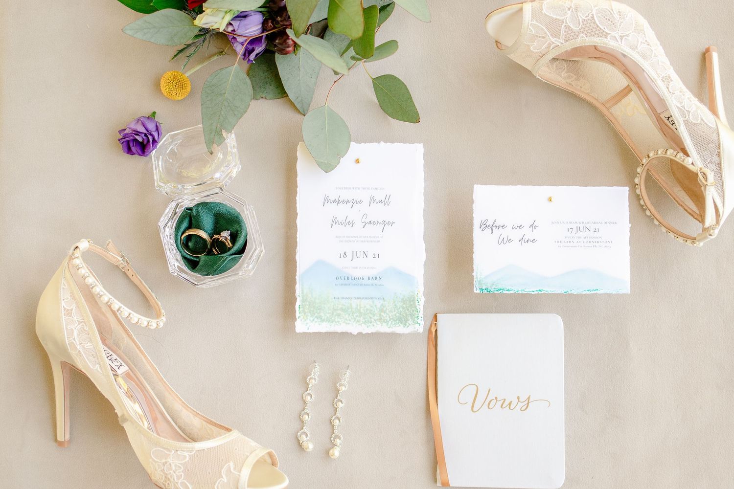Wedding detail shot with cream heels, floral invitations and crystal ring box on light background.