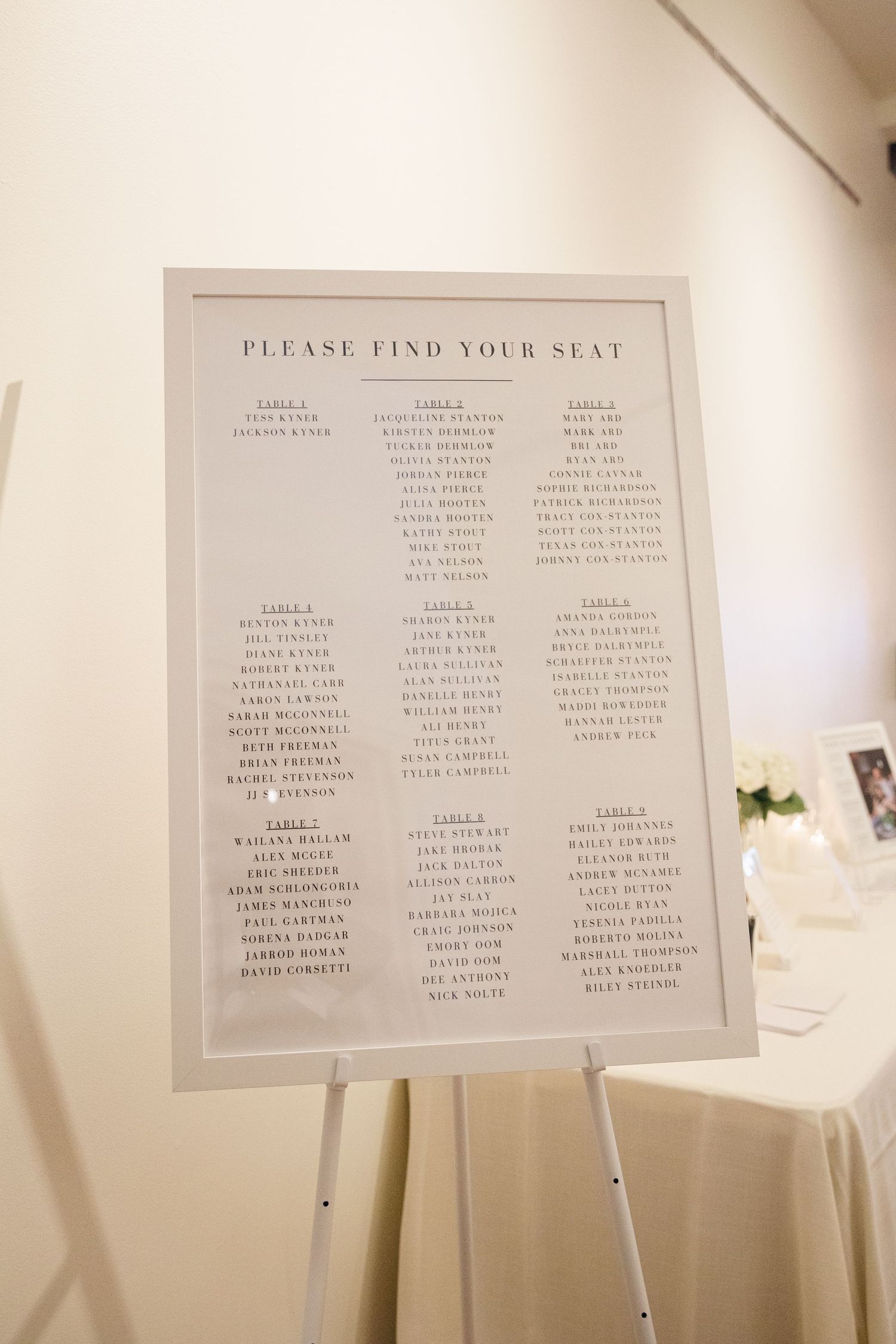 Wedding seating chart displayed on an easel with elegant typography and table assignments.