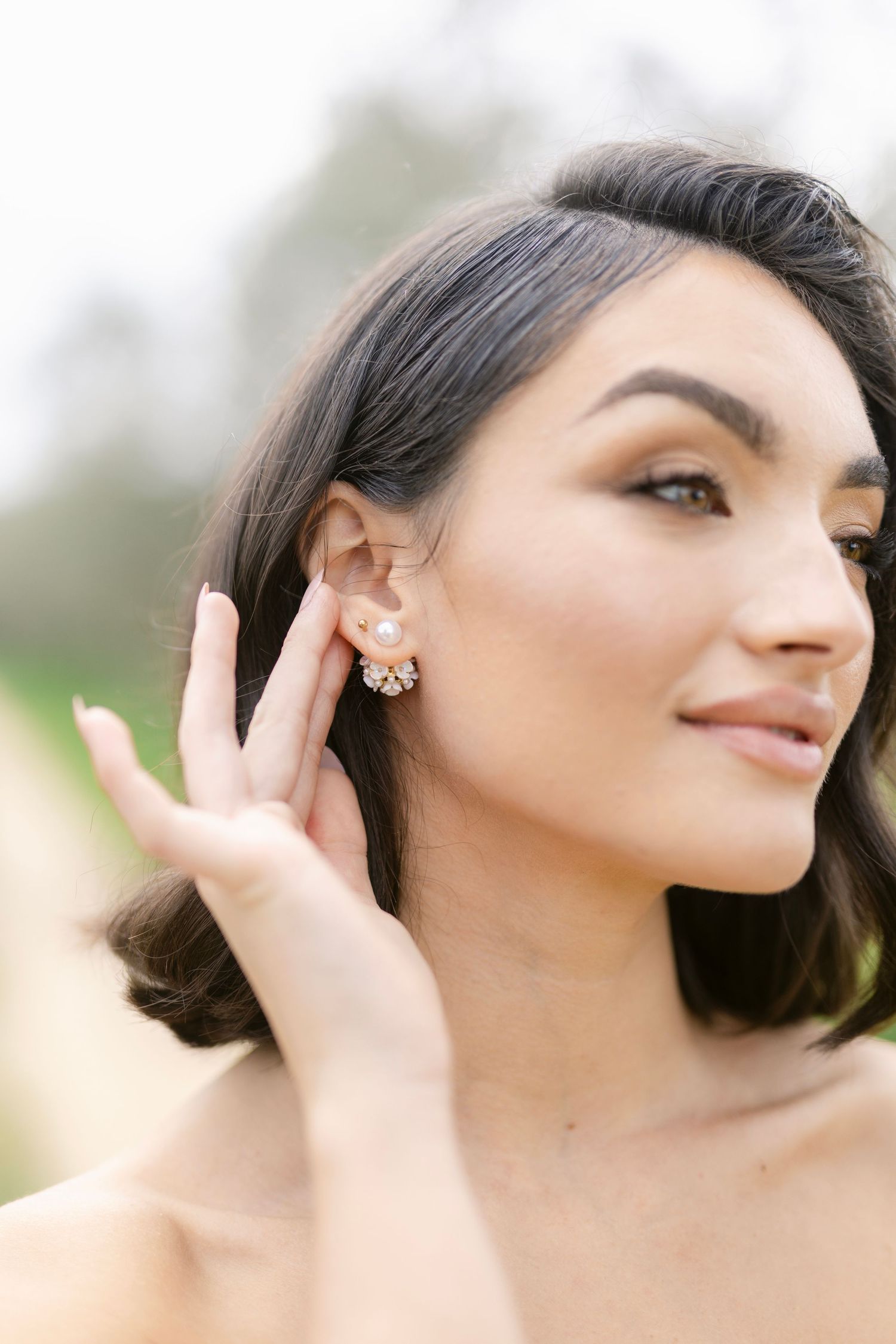 Close up artistic portrait showing delicate jewelry and elegant styling against soft natural lighting.