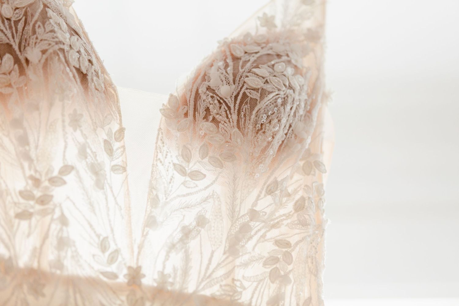 Delicate lace pattern details on a white fabric with soft beige undertones.