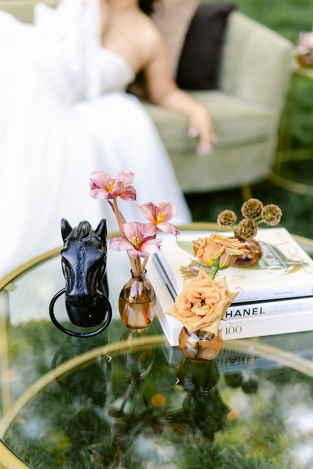 Delicate dried flowers and decorative items arranged on a glass surface with a Chanel book in the background.