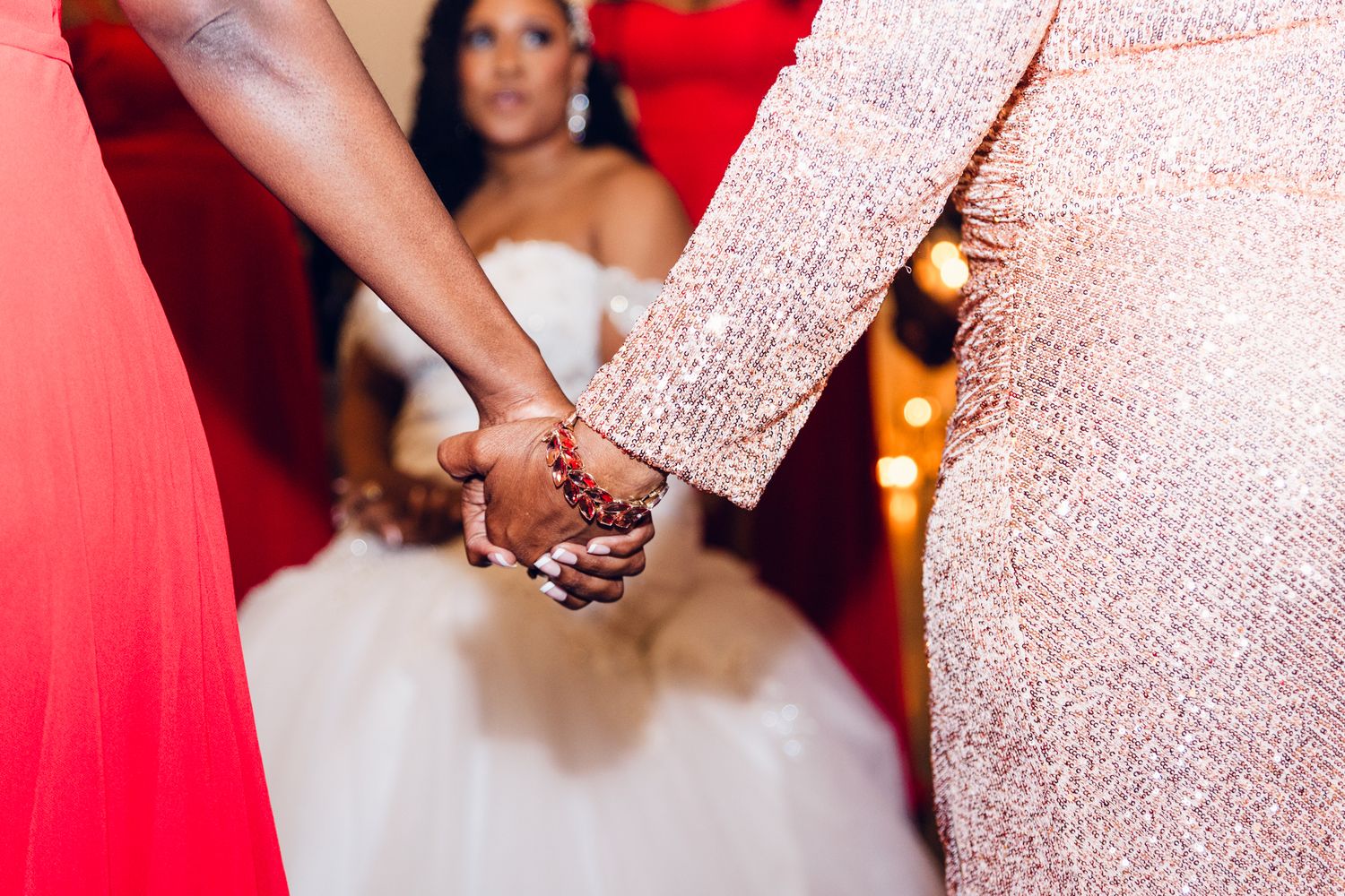Bridesmaids in vibrant red dresses celebrate during wedding reception.