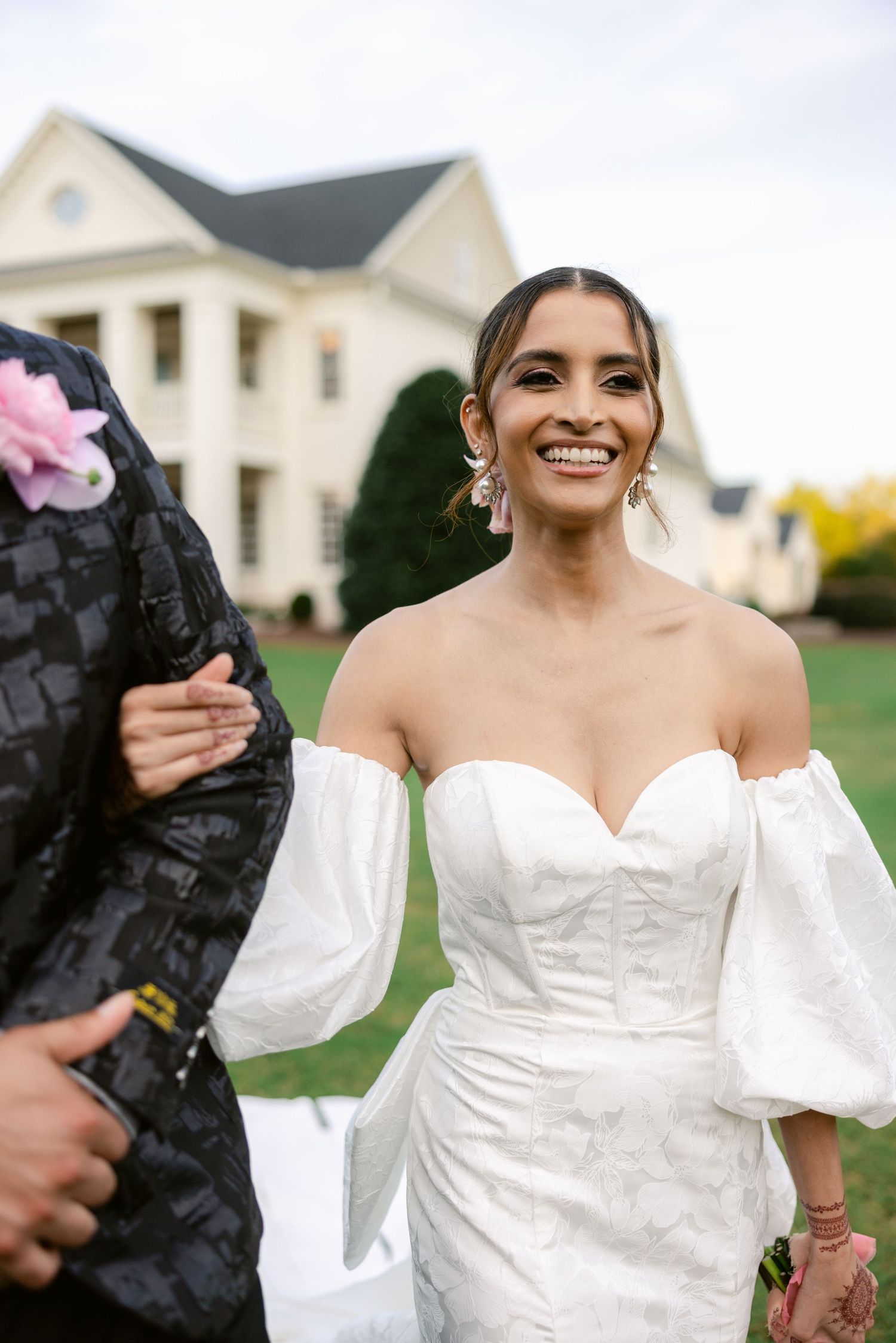 Bride in a white off-shoulder wedding gown with puffy sleeves poses during a photoshoot.