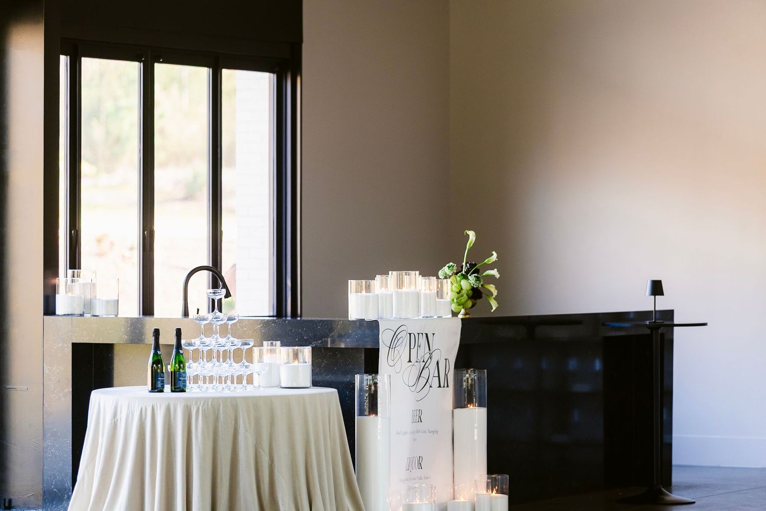 Minimalist event venue interior featuring white linen-covered tables and bar setup with natural lighting.