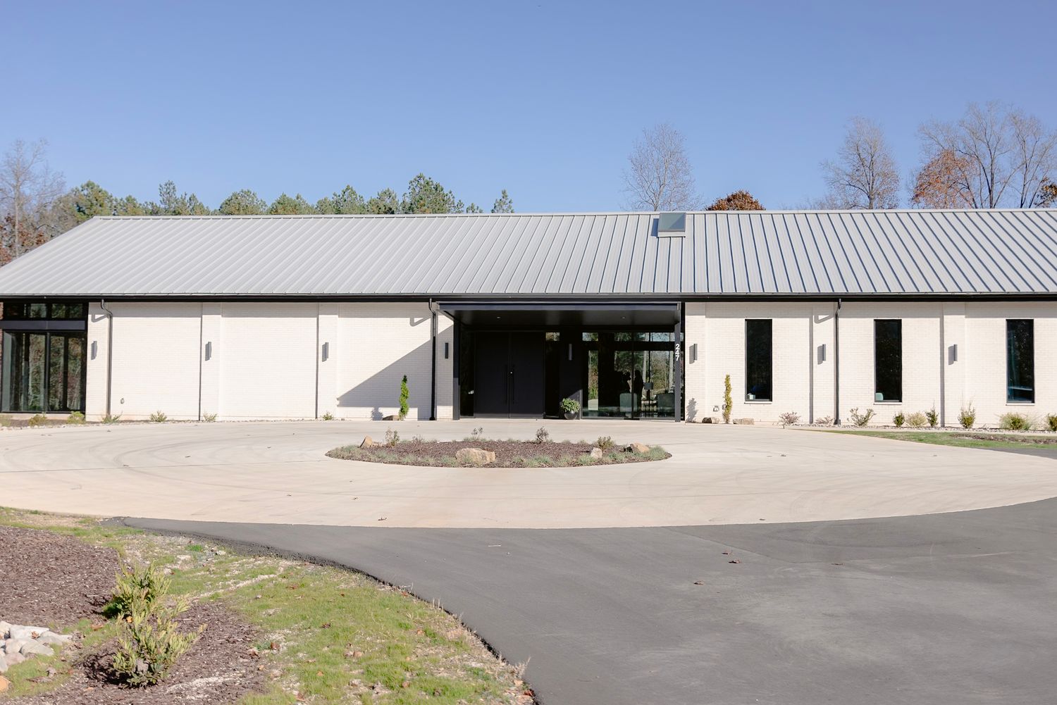 Long white commercial warehouse buildings with metal roofs and paved parking areas in an industrial complex.