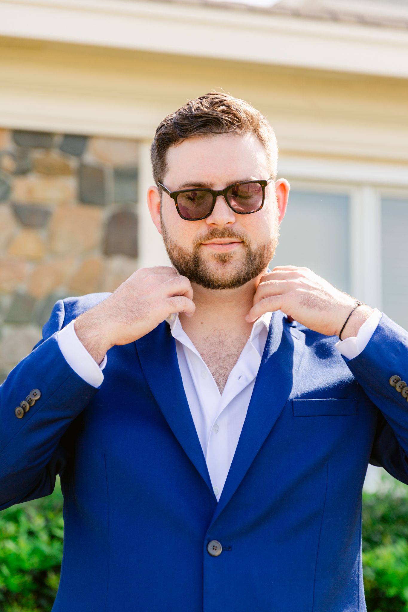 A series of close-up shots showing someone in a navy blue blazer and white shirt adjusting their collar and glasses.