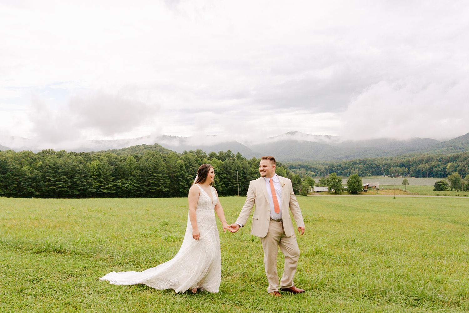 Scenic mountain landscape with couple walking through a vast green meadow.