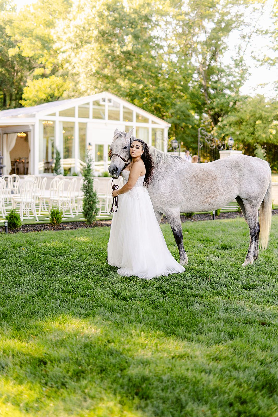 A romantic wedding photo session in a lush green field with a beautiful white horse at a countryside venue.