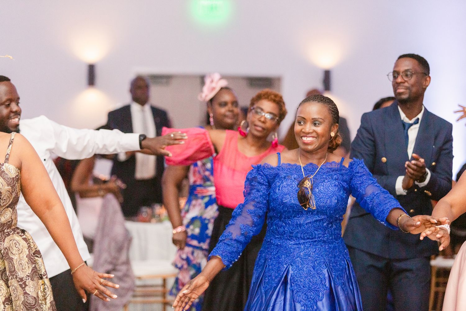 Wedding guests in royal blue dresses dancing and celebrating at the reception.