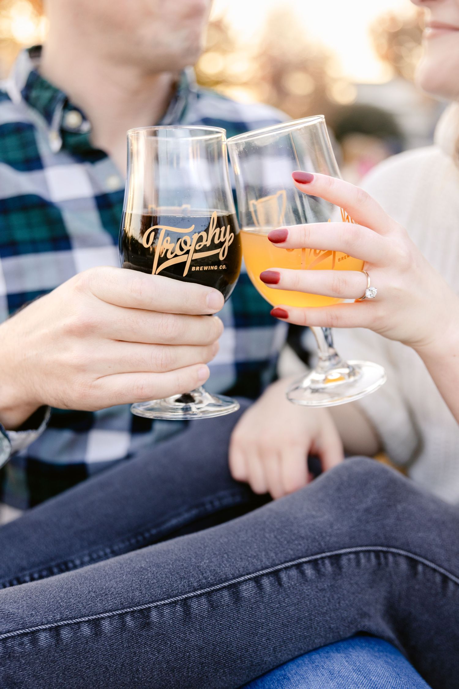Two wine glasses, one with red wine and one with white wine, clink together in a casual outdoor toast.