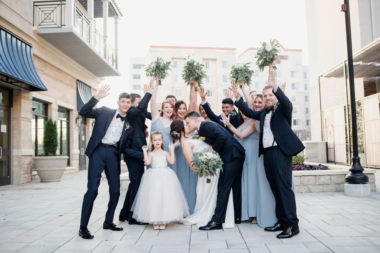 Wedding party celebrating outdoors in formal attire with joyful expressions.
