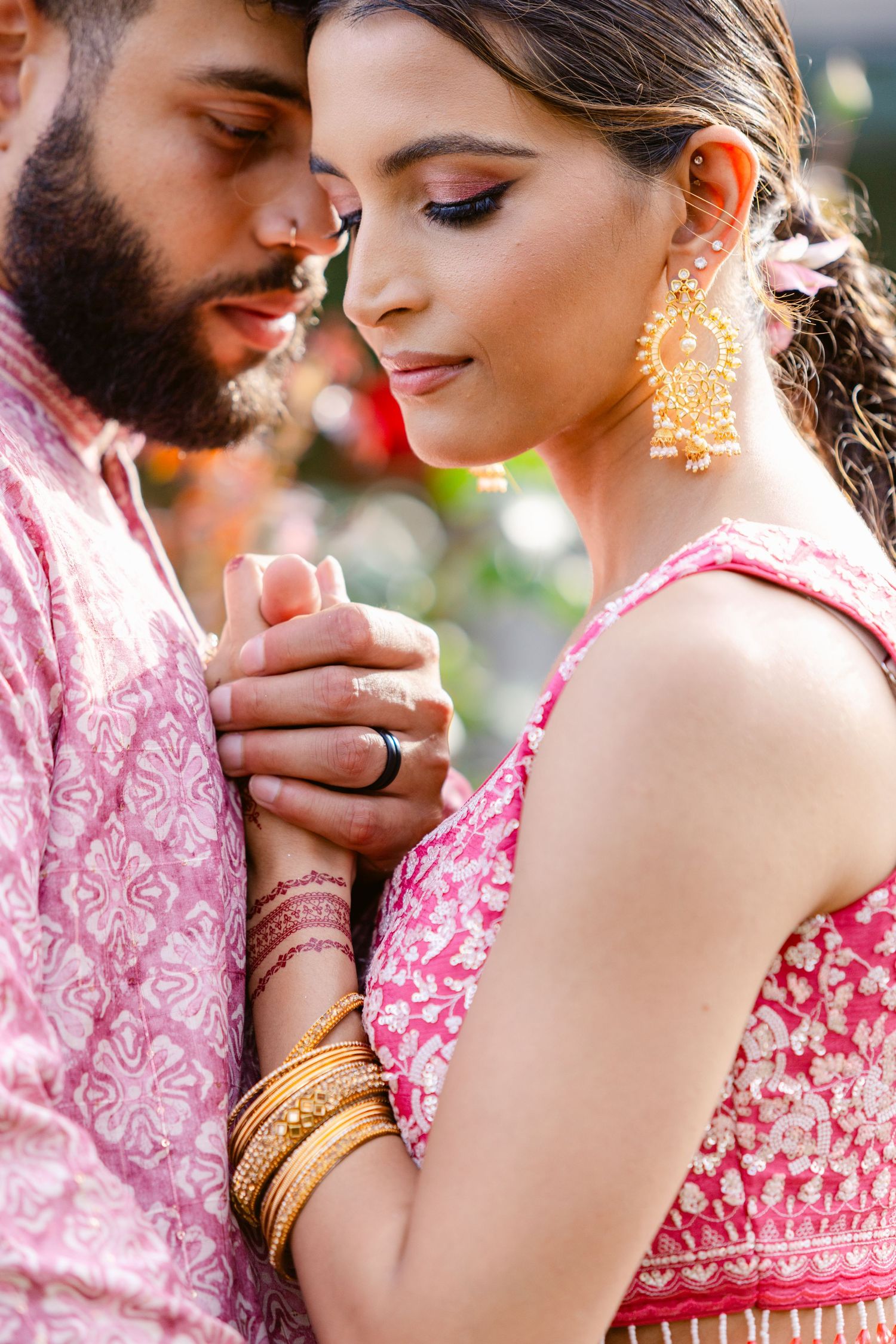 Romantic couple in traditional pink Indian wedding attire sharing an intimate moment.